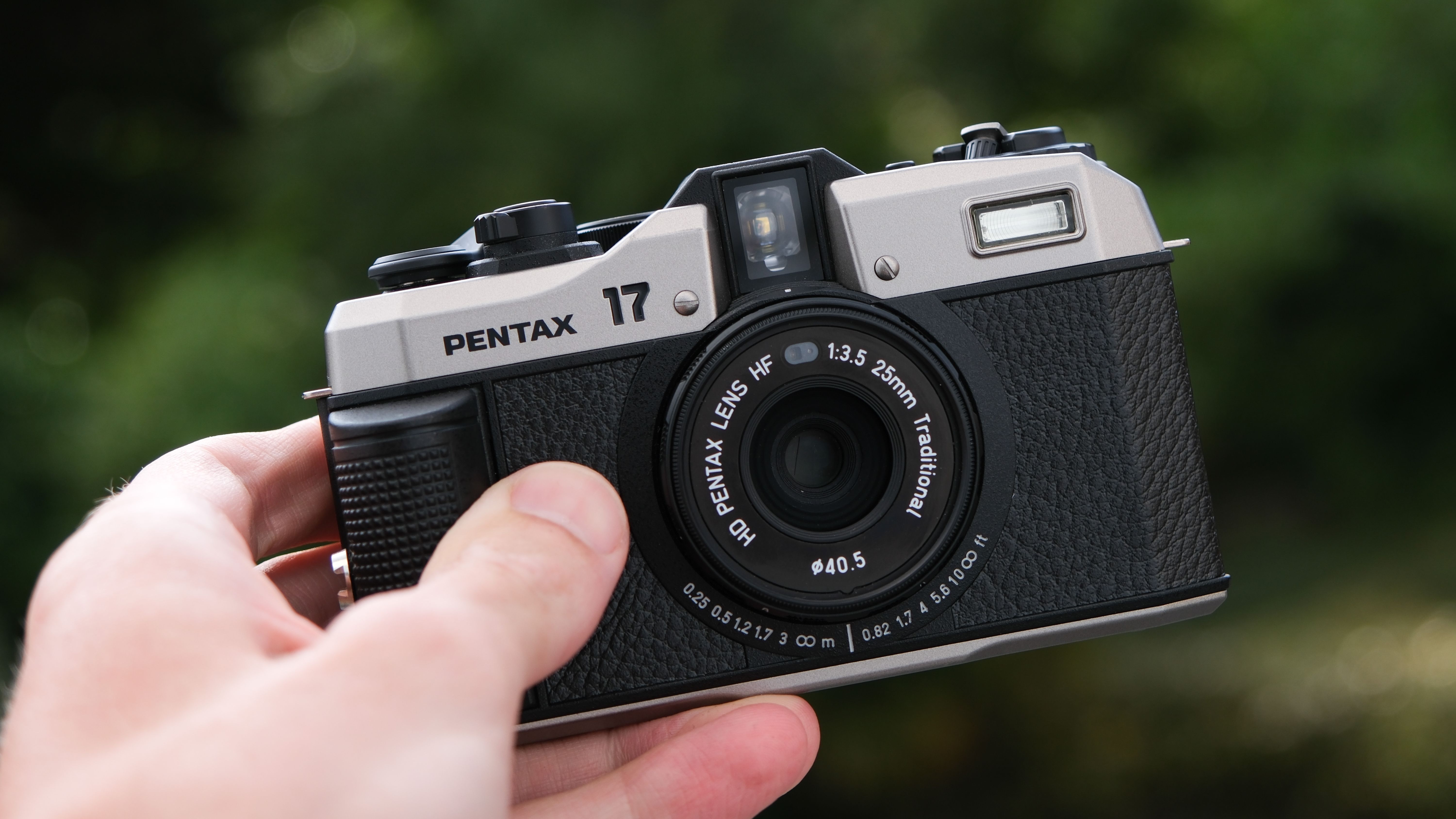 A Pentax 17 film camera held in a hand outside