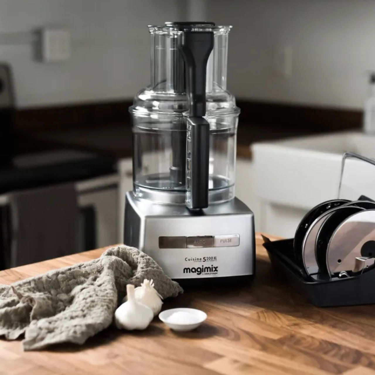 Magimix food processor on a wooden countertop with a wipe beside it