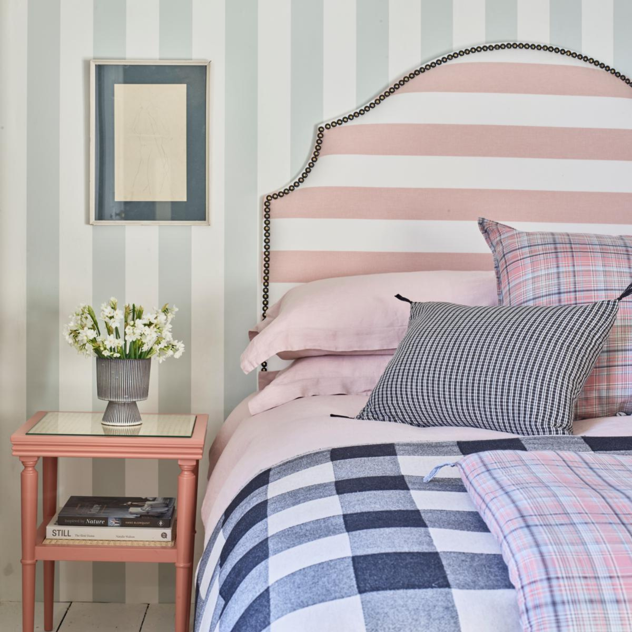 a bedroom with striped wallpaper, a striped headboard, and checker printed bedding