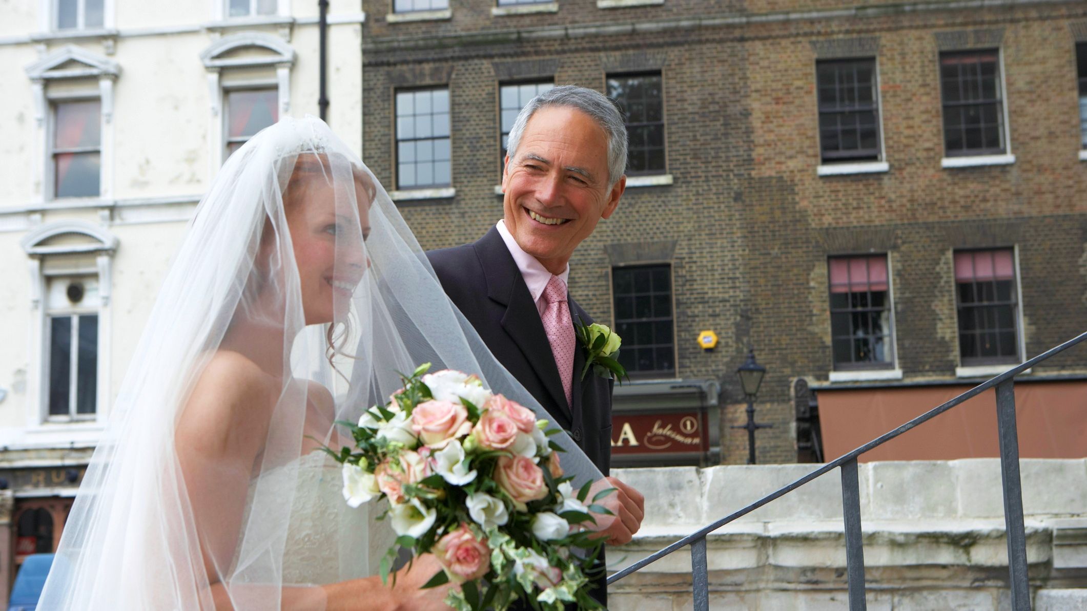 The father of the bride walks his daughter up the church stairs to the wedding.