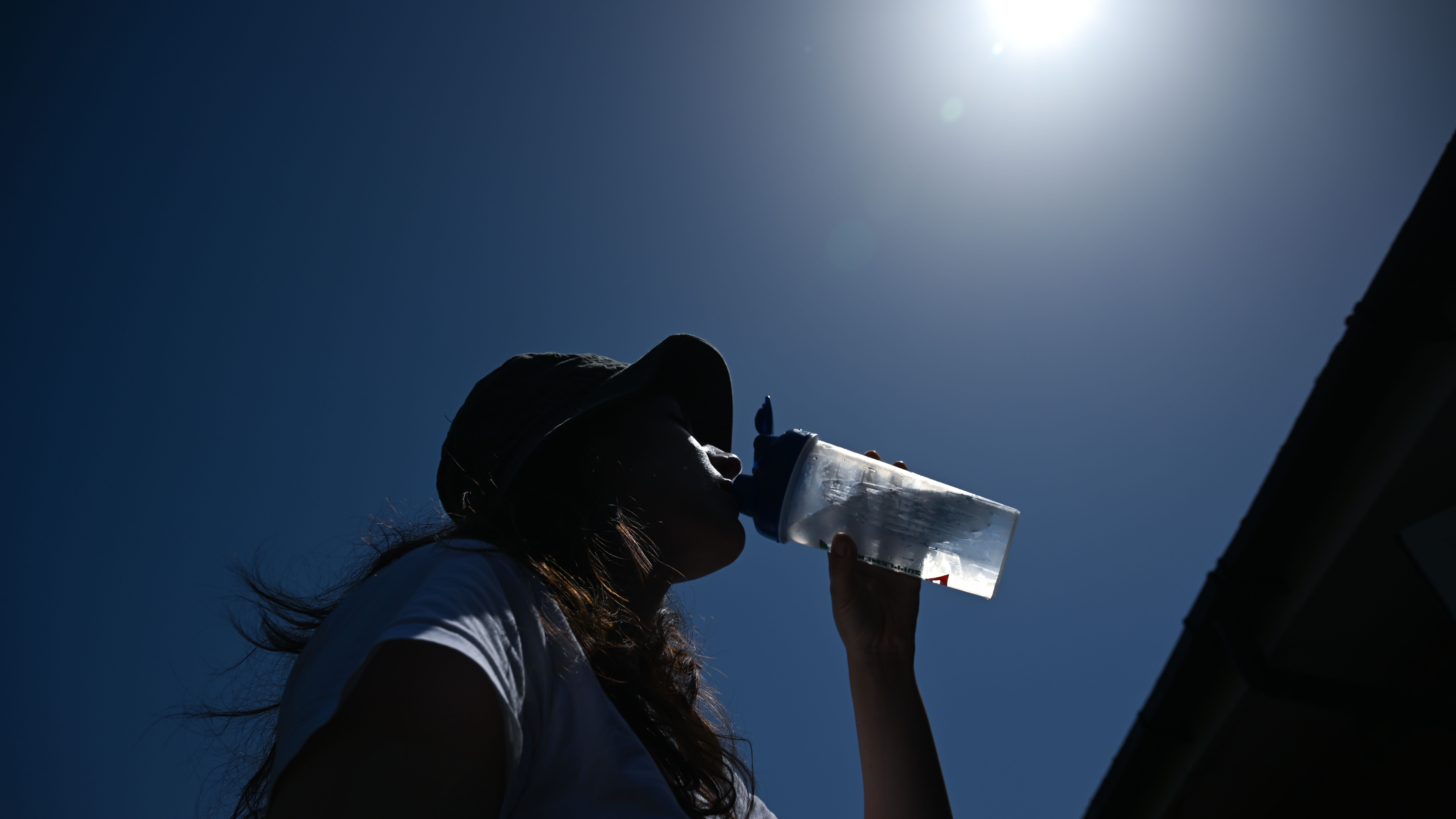 A woman tries to cool down by drinking water during a heatwave in London