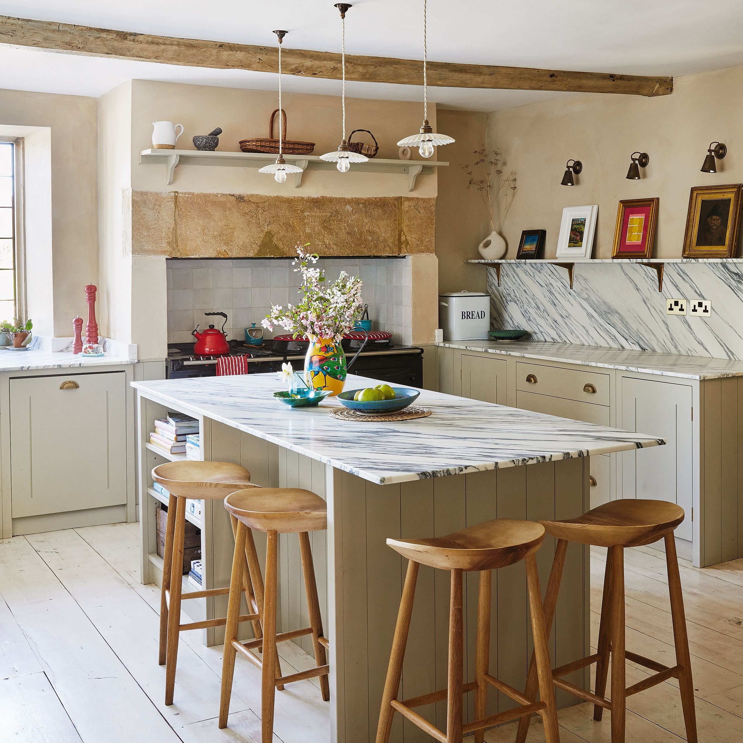 modern country kitchen with island with marble worktop, wooden bar stools, pendant lights, range cooker and shaker style units