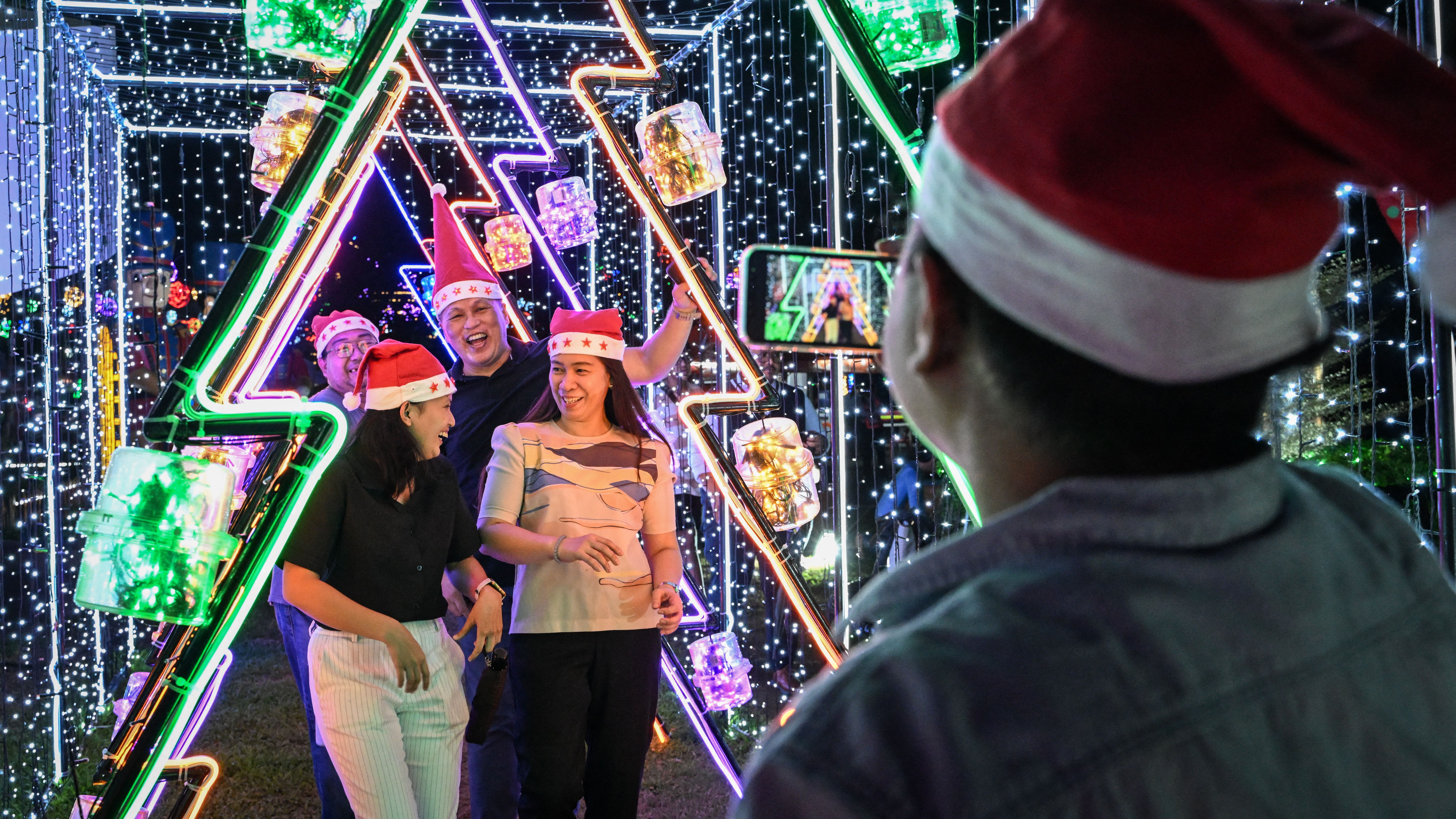 Visitors pose for photos with Christmas decorations at Meralco Liwanag Park in Pasig City, Metro Manila on December 9, 2024. (Photo by JAM STA ROSA / AFP)