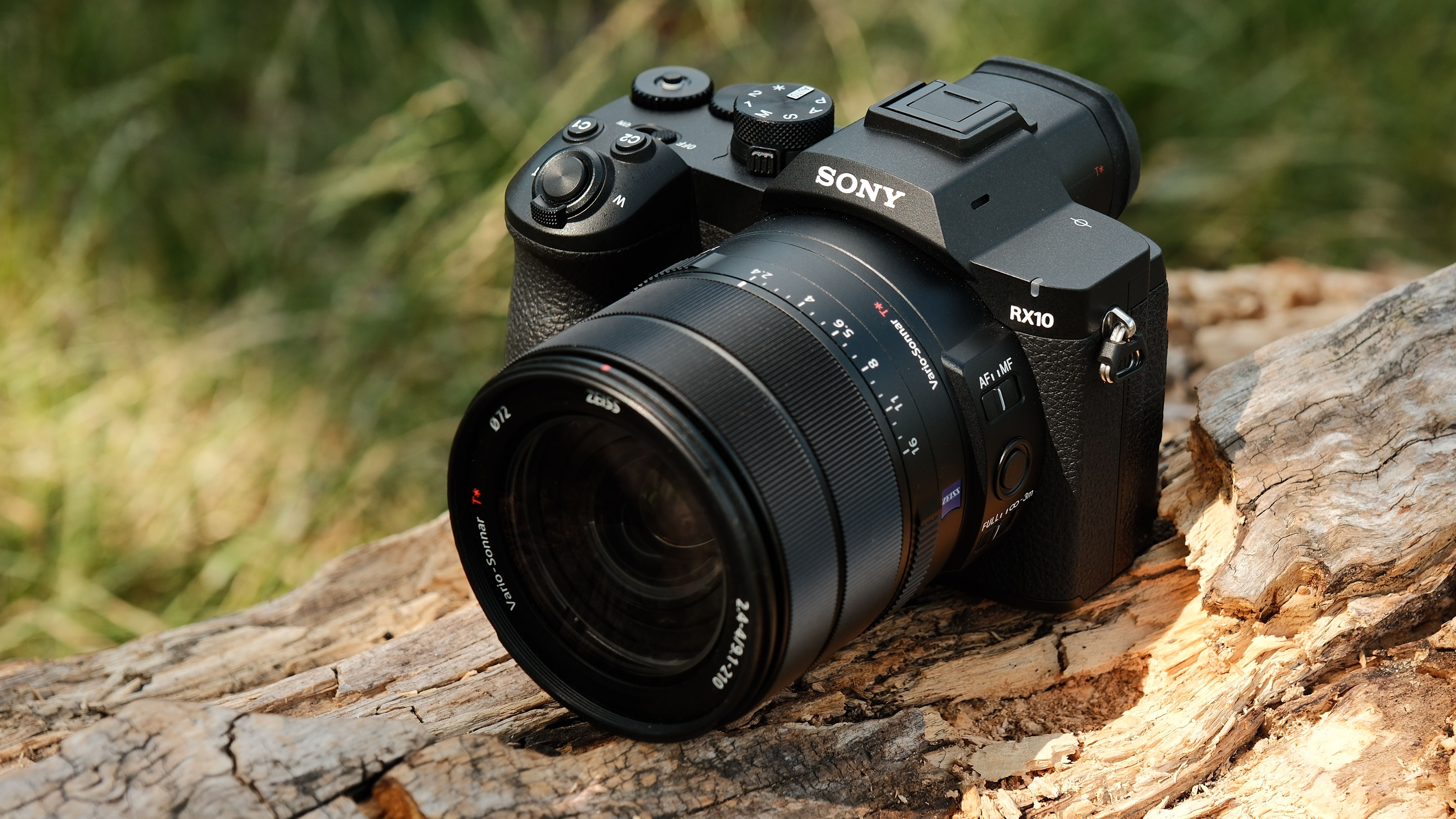 Front three-quarter view of the Sony RX10 V on a log in bright sunlight.