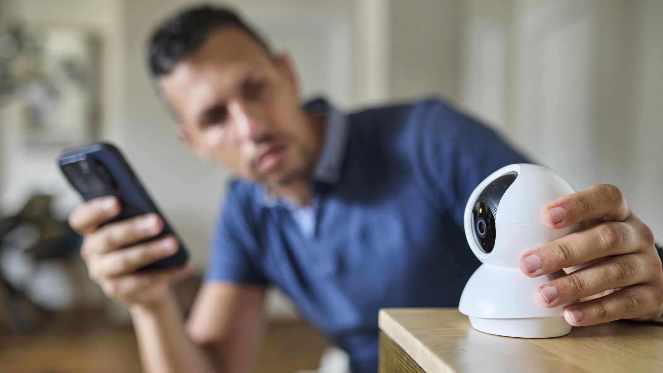 Man Setting Up Smart Webcam Using Smartphone at Home