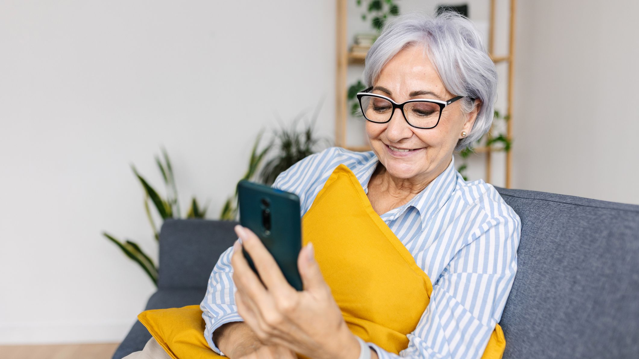 Happy woman laughing while watching media content on smartphone app at home.