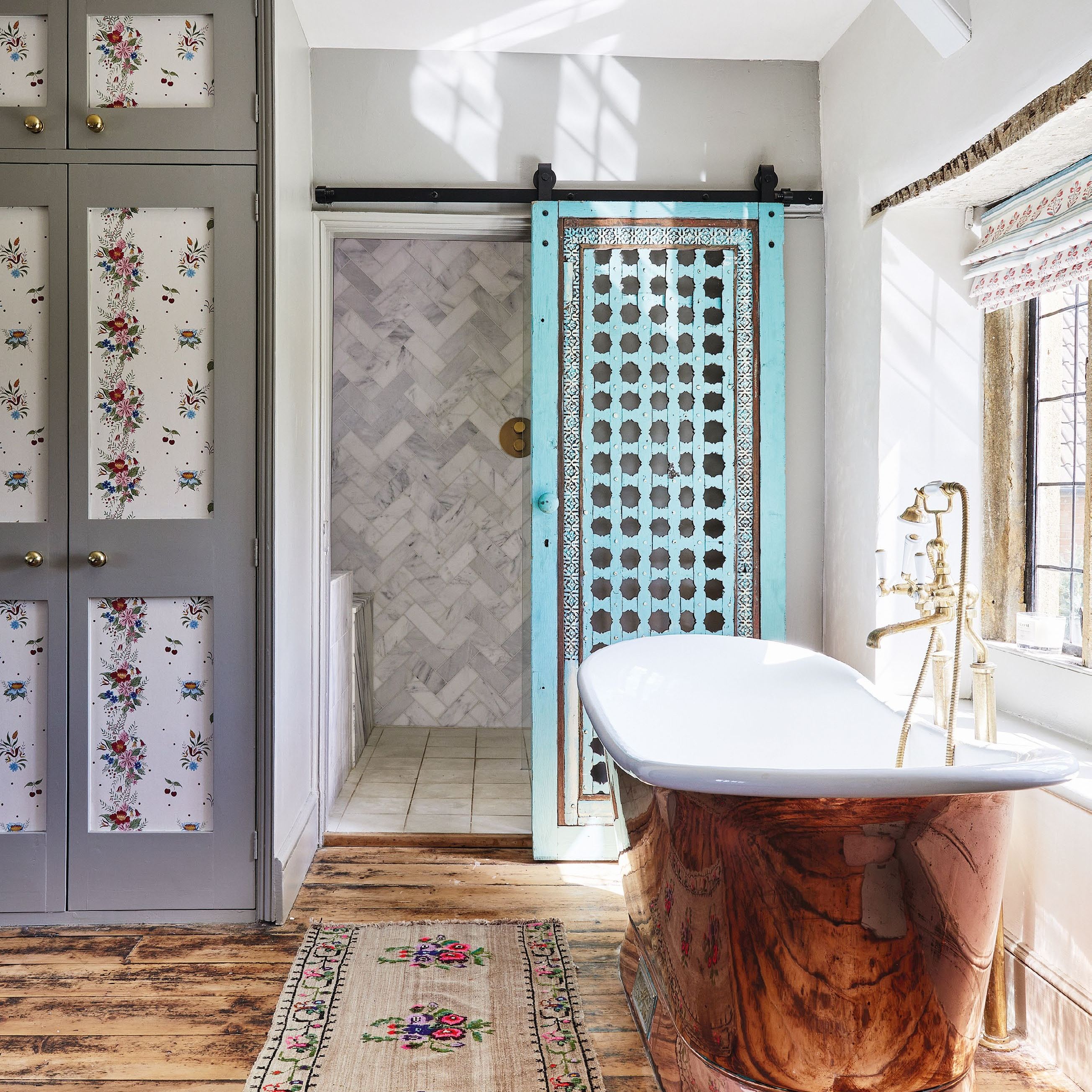 Bathroom in old house with copper bath tub, reclaimed doors on shower and wooden floor