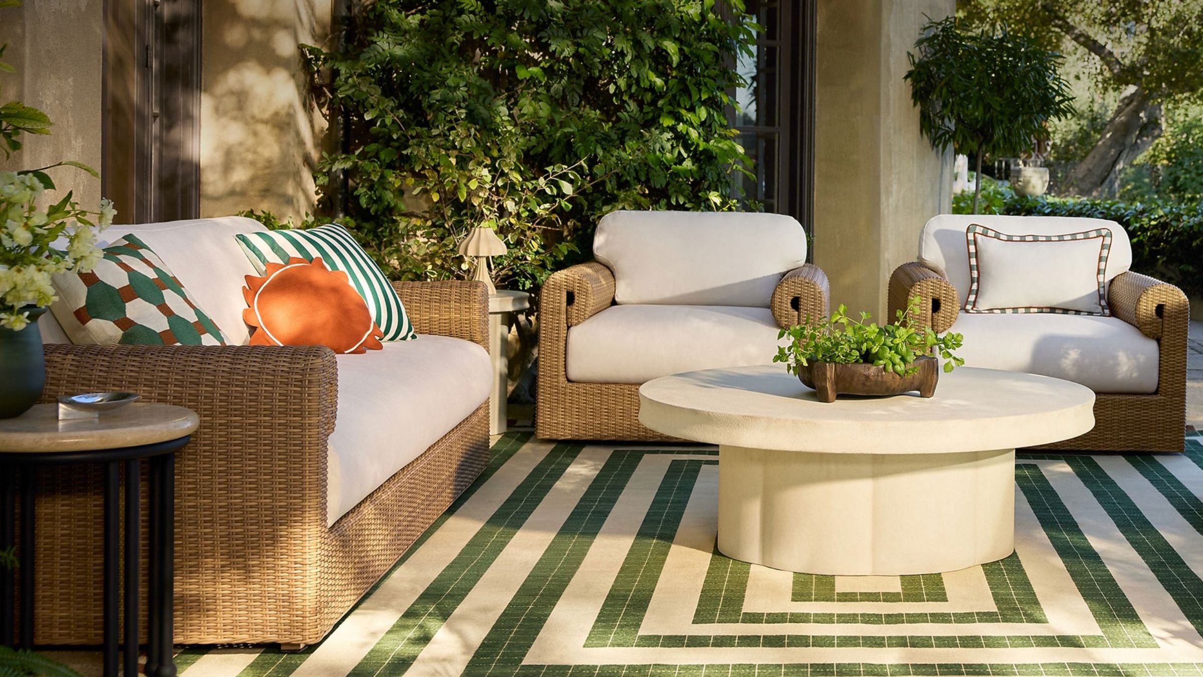 Outdoor living area with tile-effect green and white rug and rattan seating