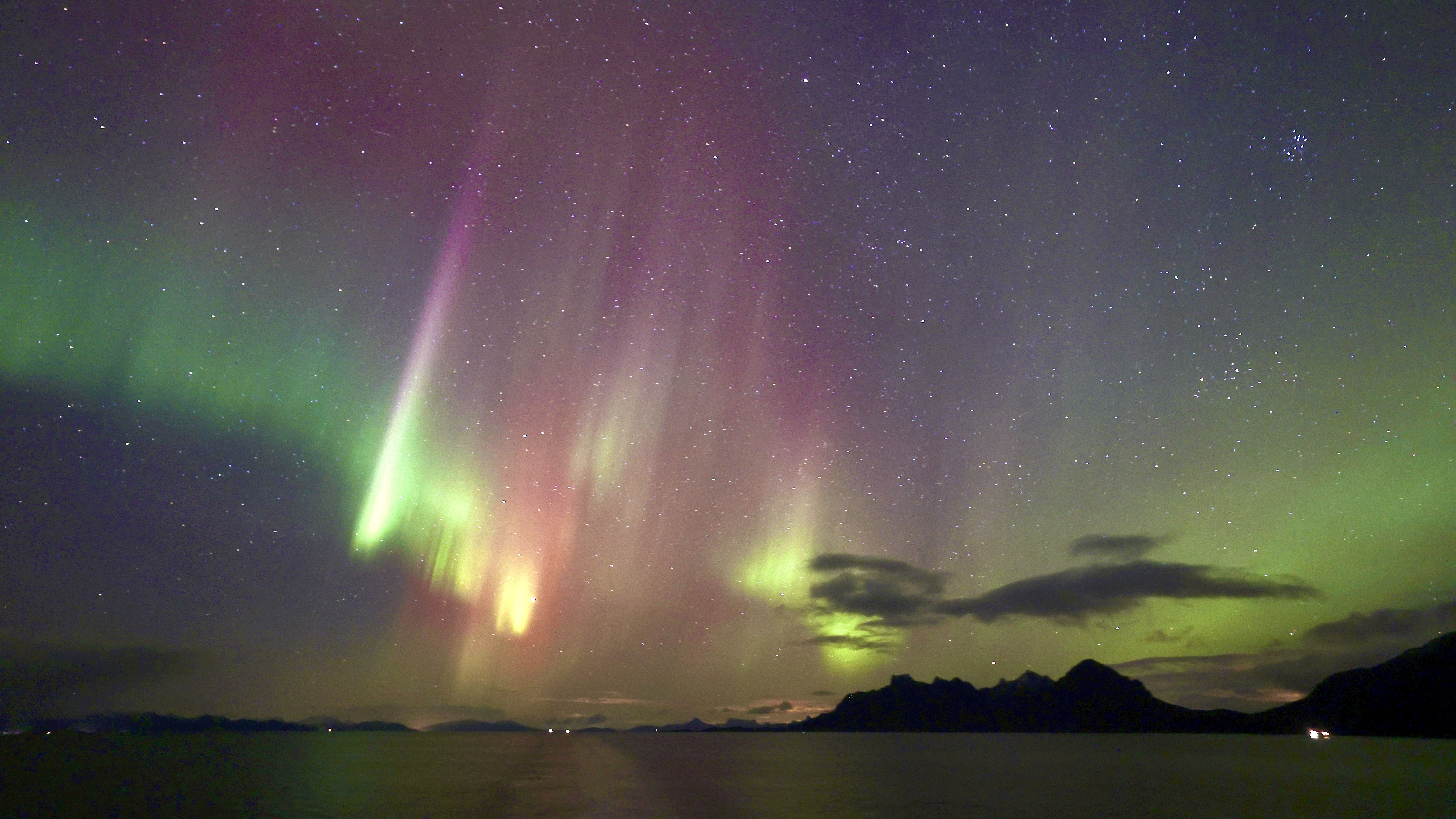 northern lights colored green, magenta and slightly yellow stretch through the sky.