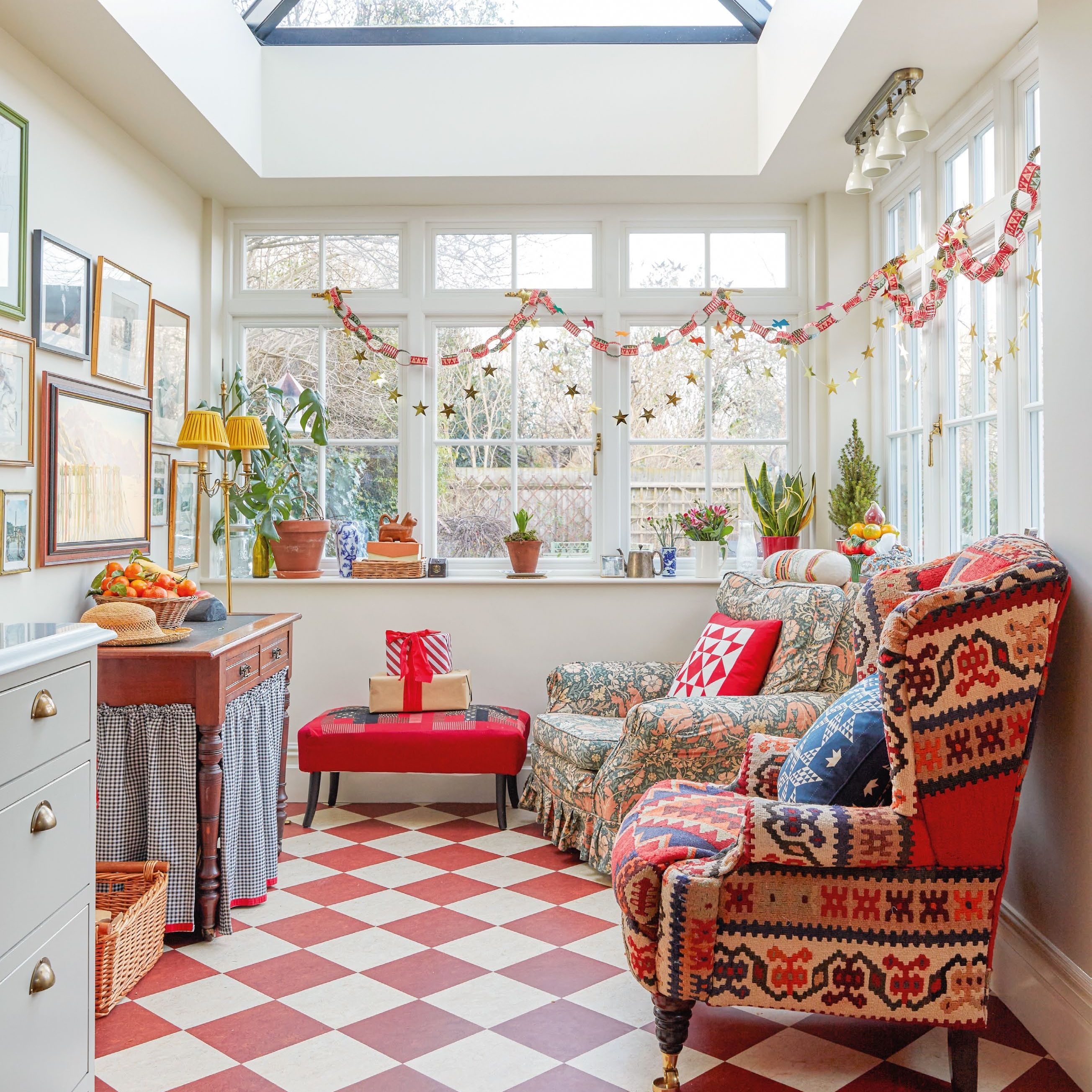 snug area of kitchen diner with double aspect windows, red and white chequered floor and patterned vintage armchairs