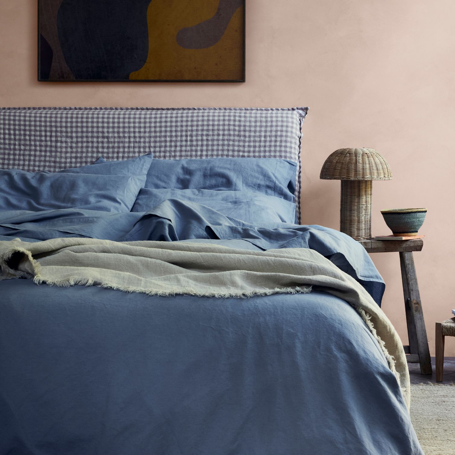 A bedroom with a blue bed and pink walls