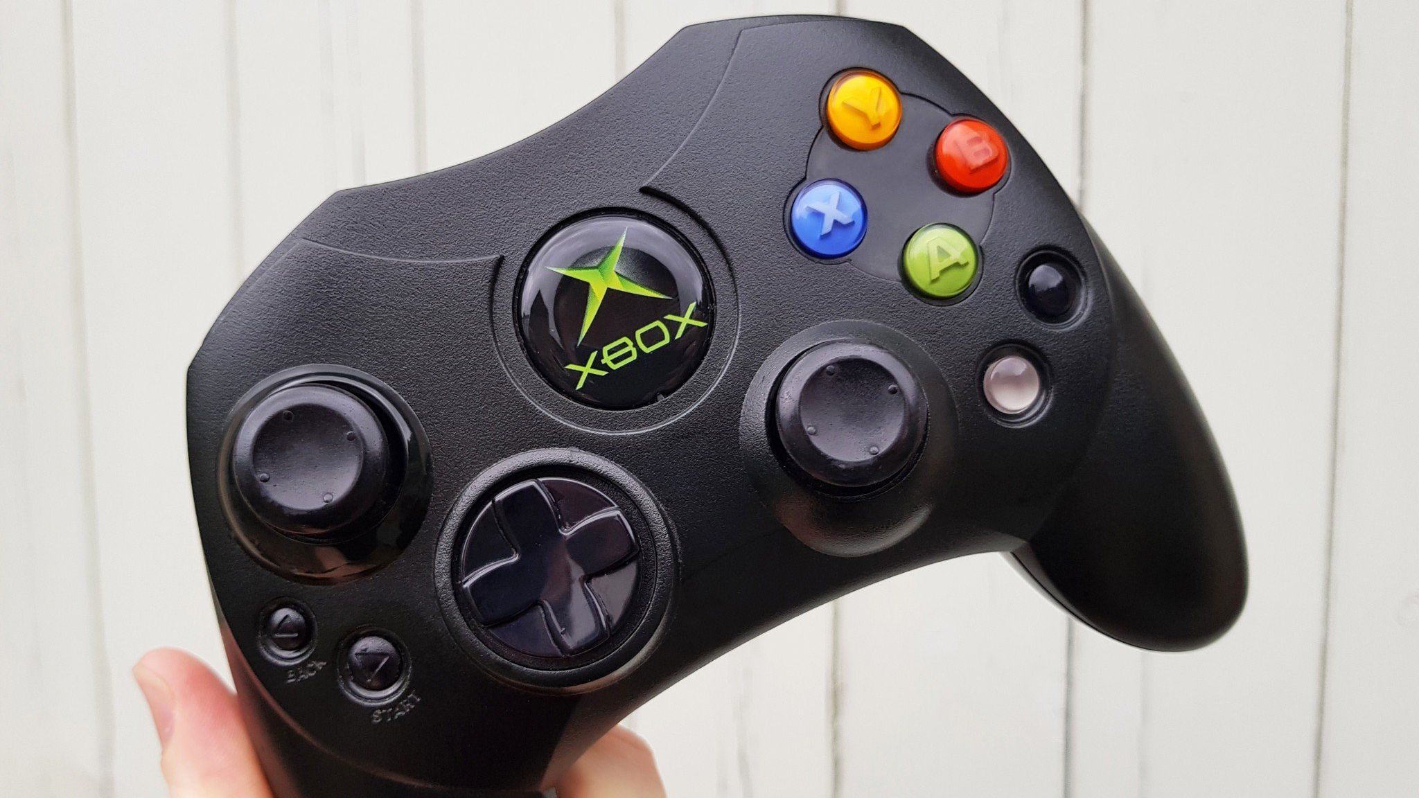 Original Xbox controller held in hand against a white background.