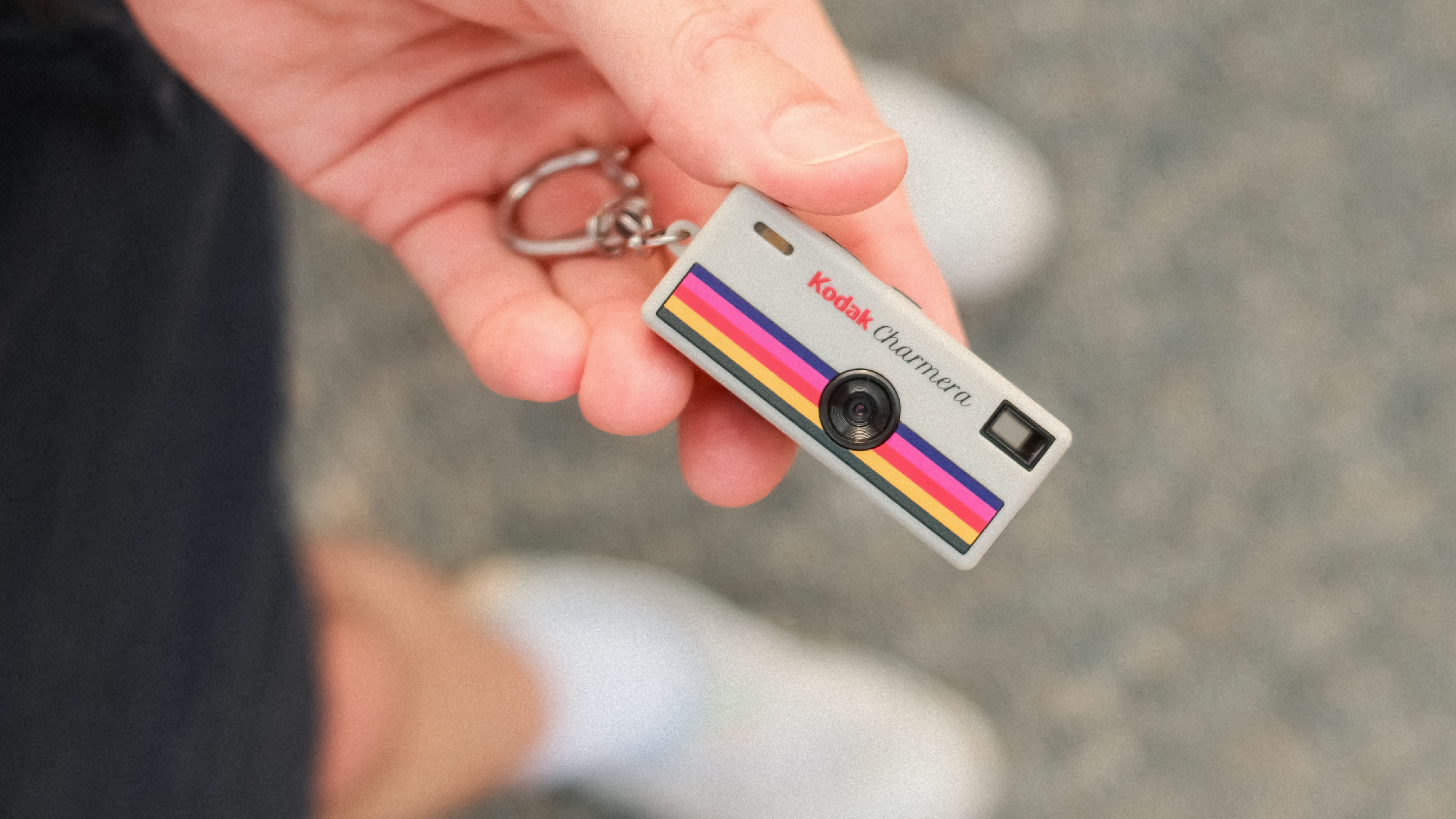 Close-up of a Kodak Charmera miniature camera keychain held in one hand.