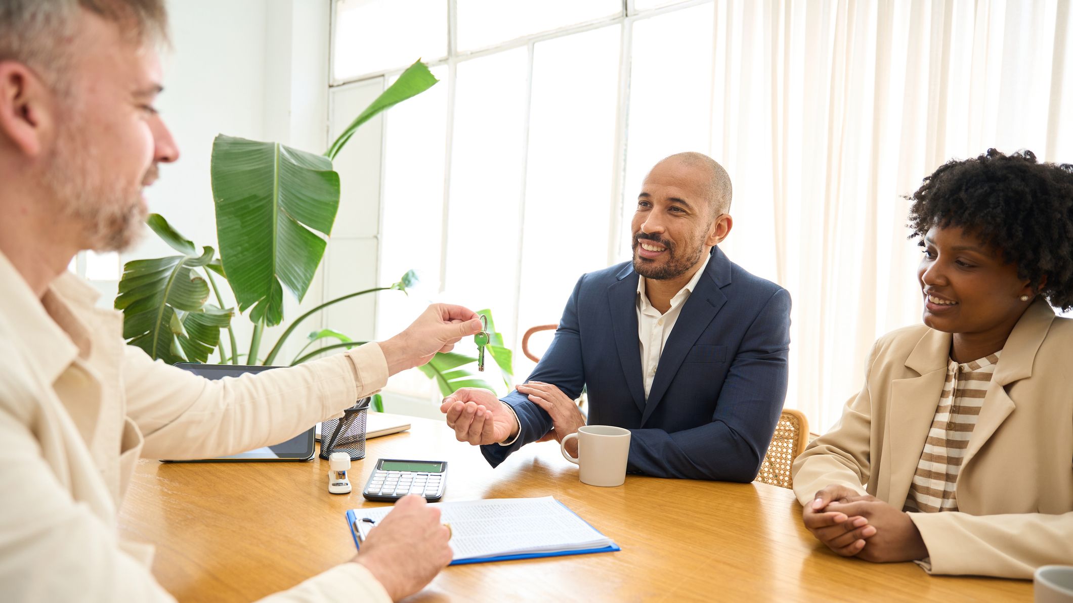 Real estate agent giving keys to a couple in his office