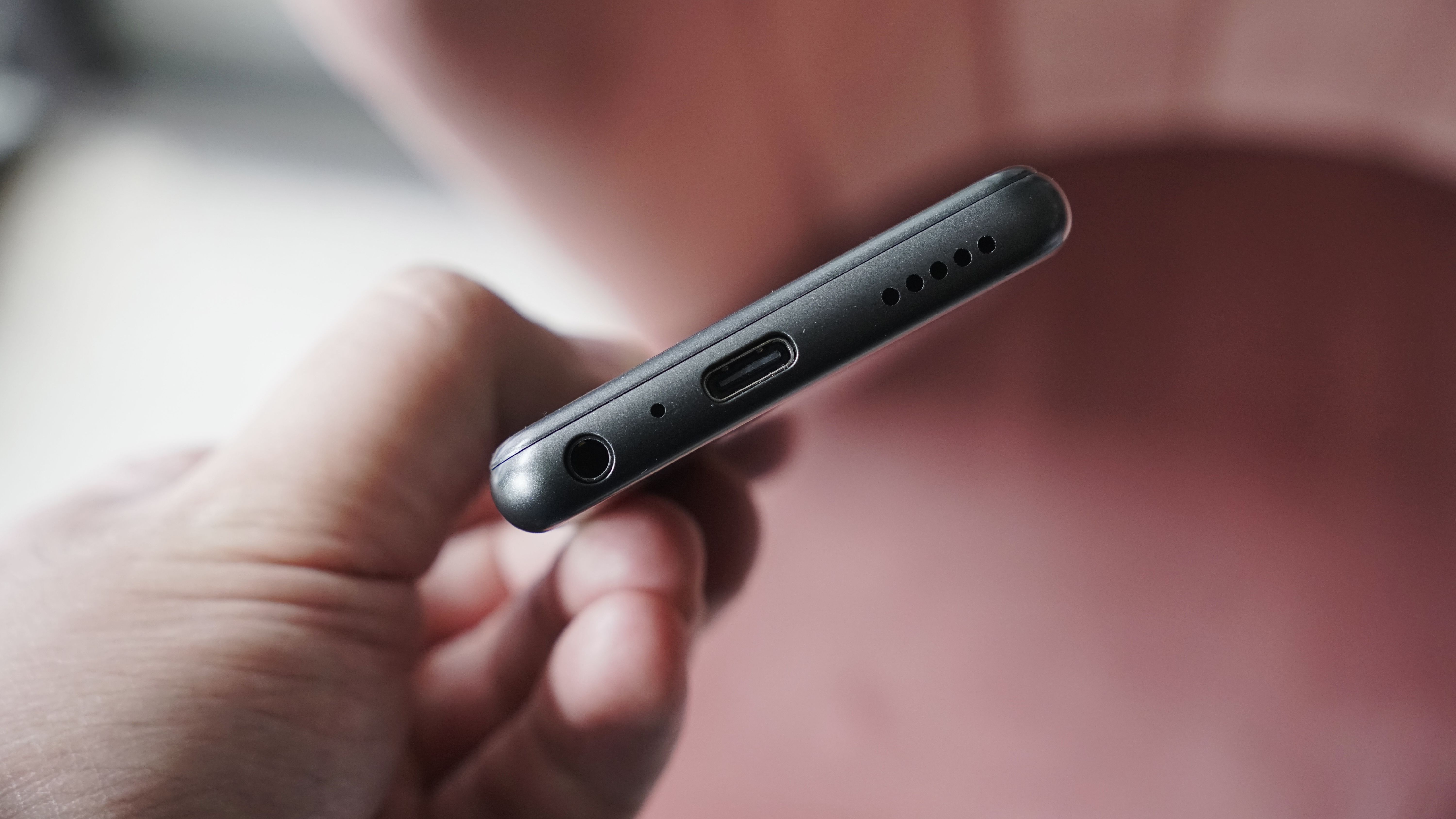 Innioasis Y1 player held in a man's hand, showing the dial and screen, with a wooden table in the background