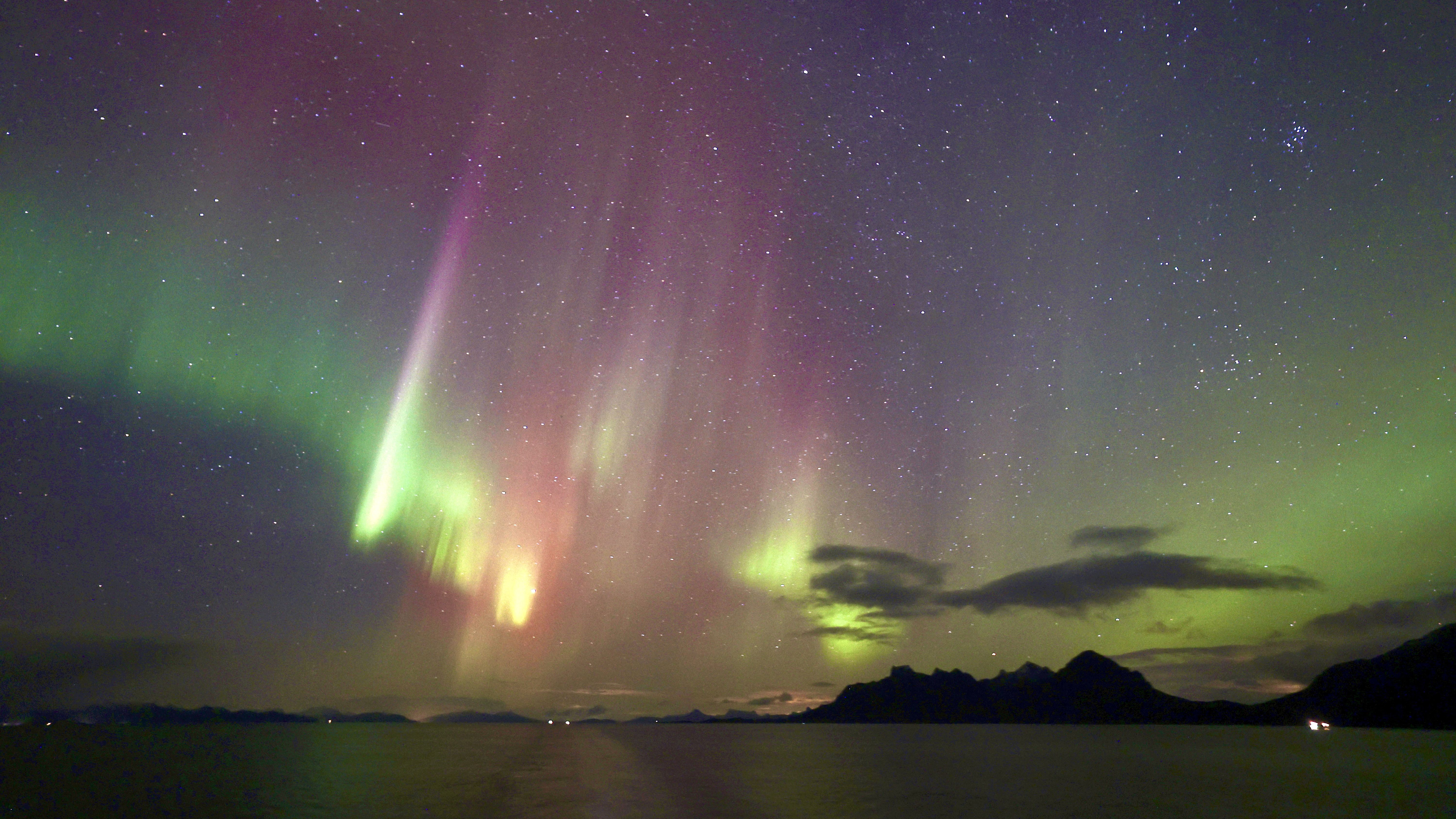 northern lights colored green, magenta and slightly yellow stretch through the sky.