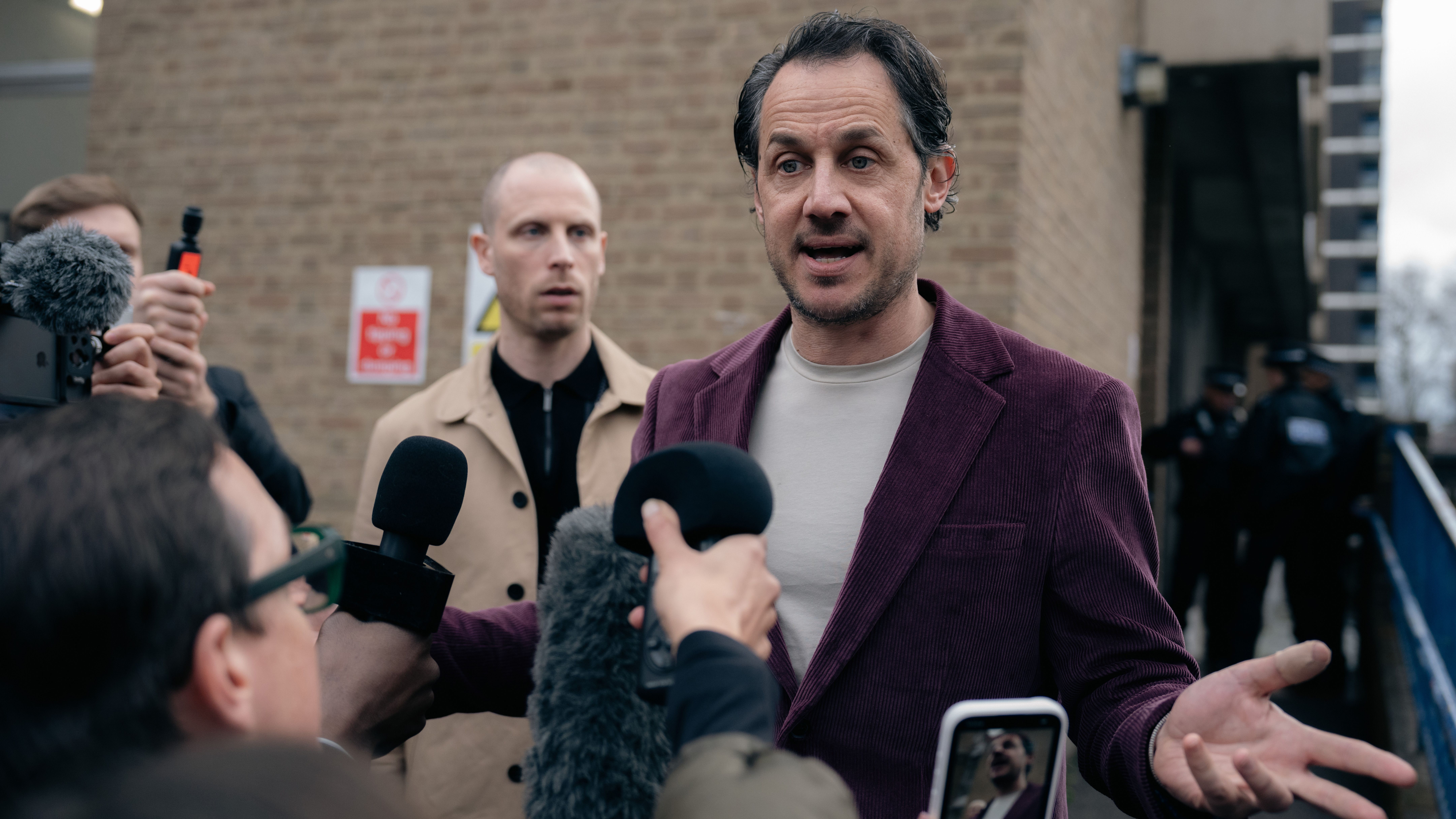 a production image from Criminal Record season two showing a man in a blazer addressing a crowd of reporters