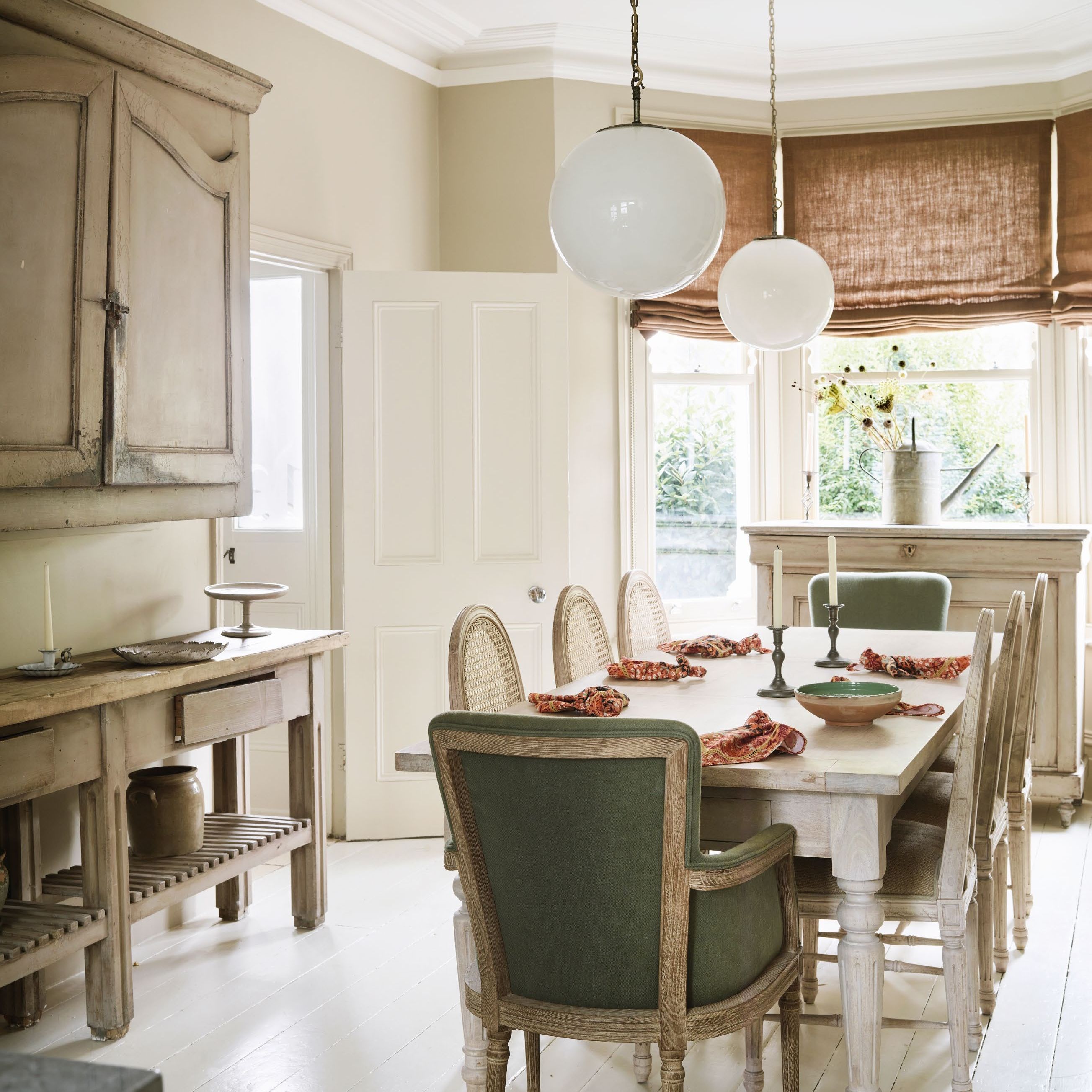 pale decorated open plan kitchen dining space with a mix of new and antique furniture and globe pendant lights
