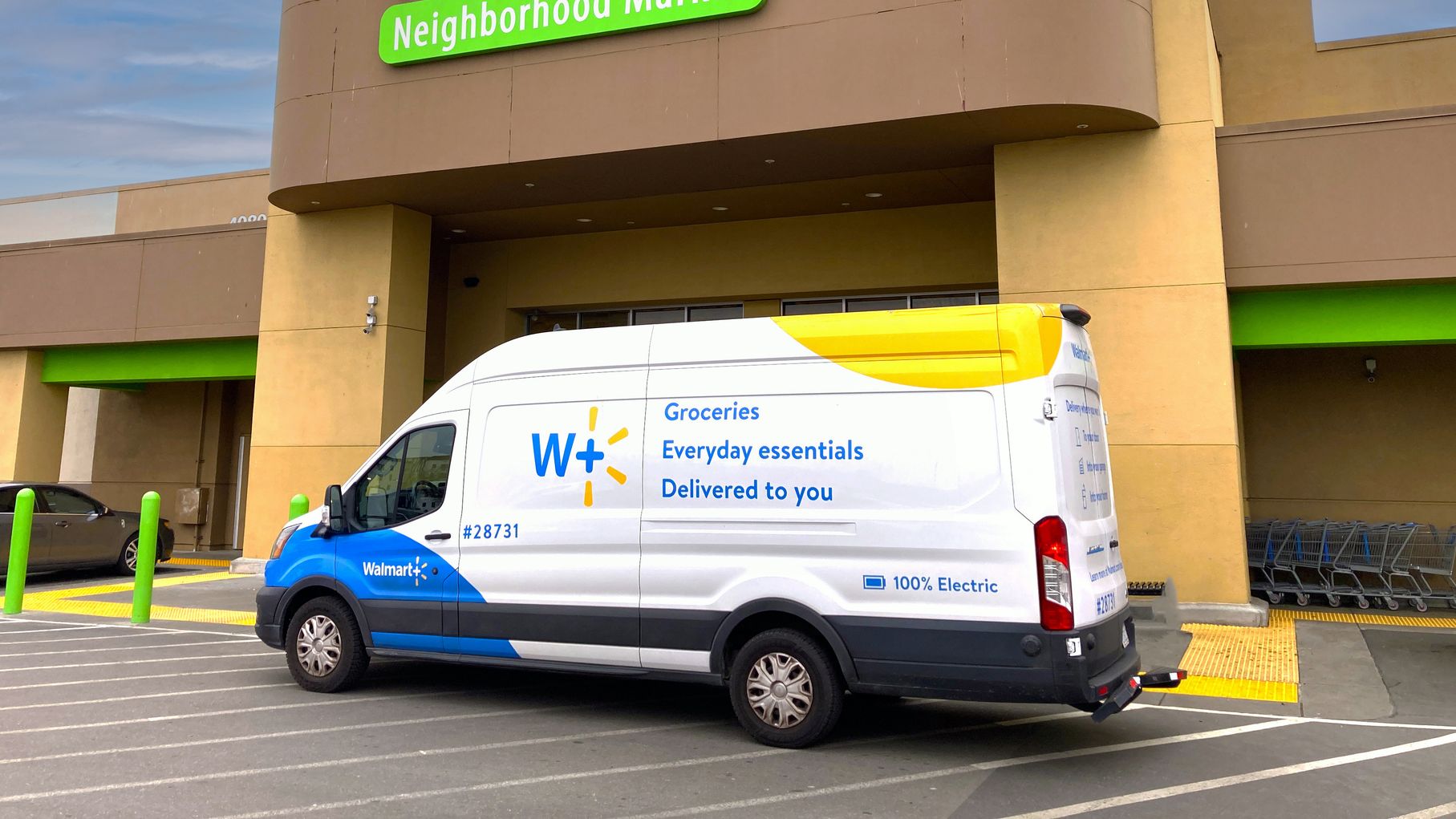 A walmart plus delivery van parked outside a walmart store.
