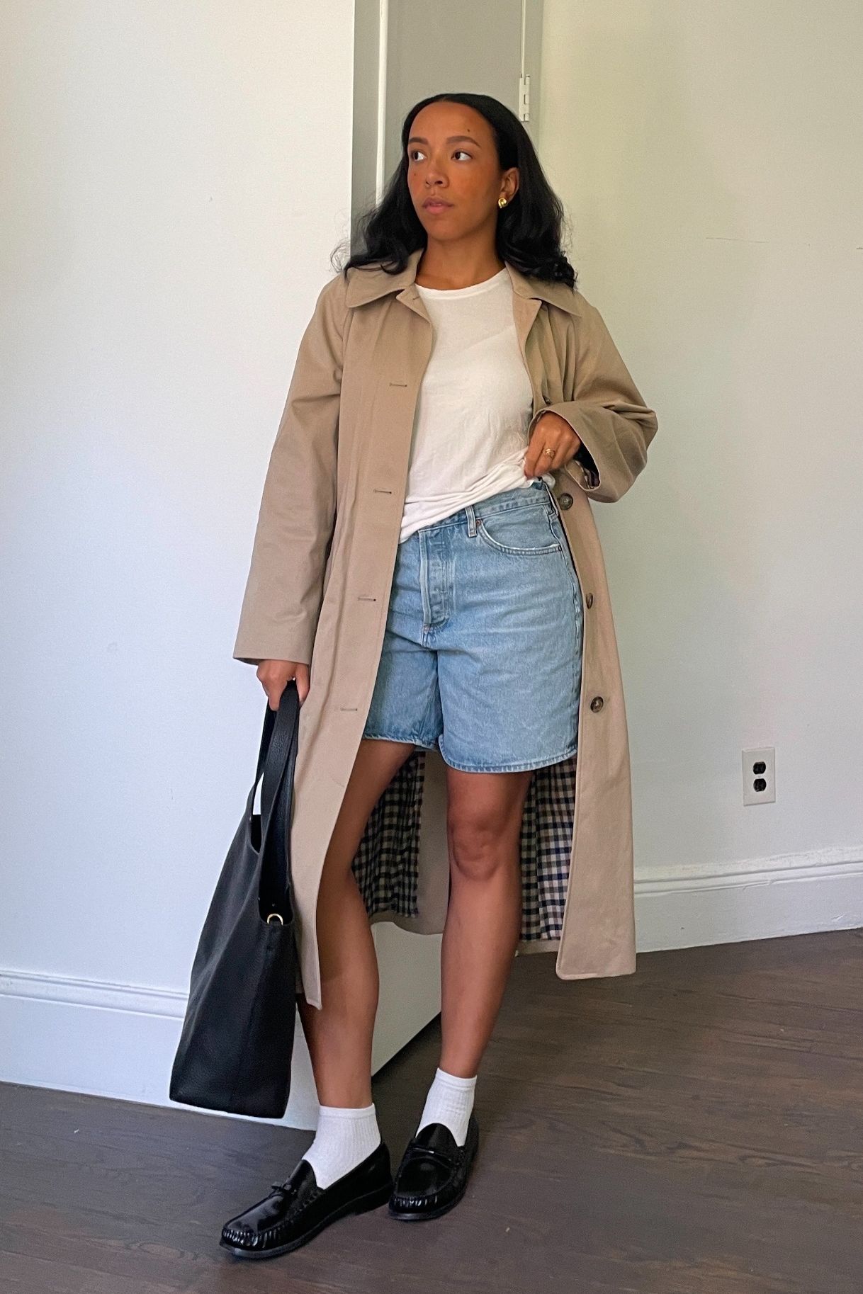 Lauren Tappan wearing a white tee, a trench coat, and denim Bermuda shorts