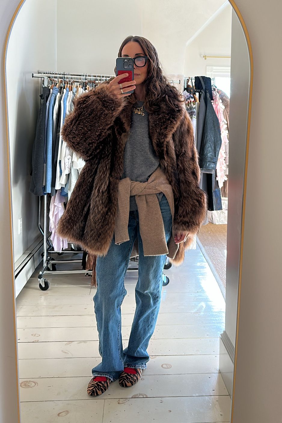 Larissa Mills in a grey sweater, brown fur coat, and blue jeans