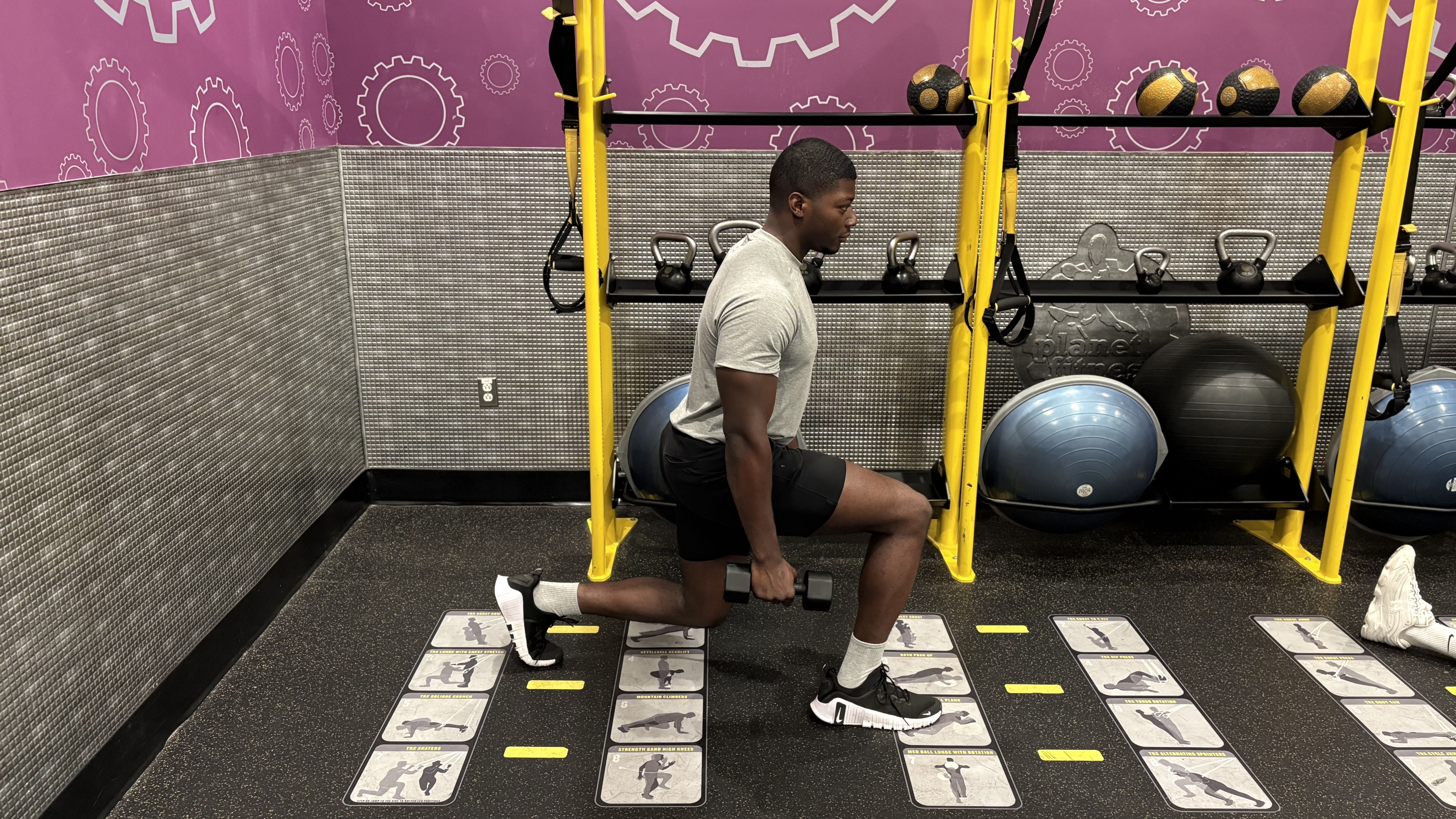 Man demonstrates a dumbbell exercise in a gym