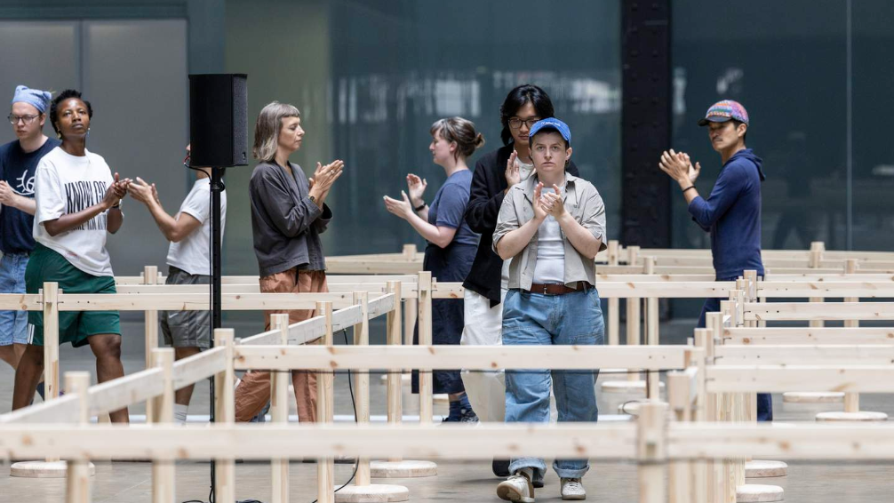 an image of people walking through the Turbine Hall Serenity Island exhibition installation, clapping on cue
