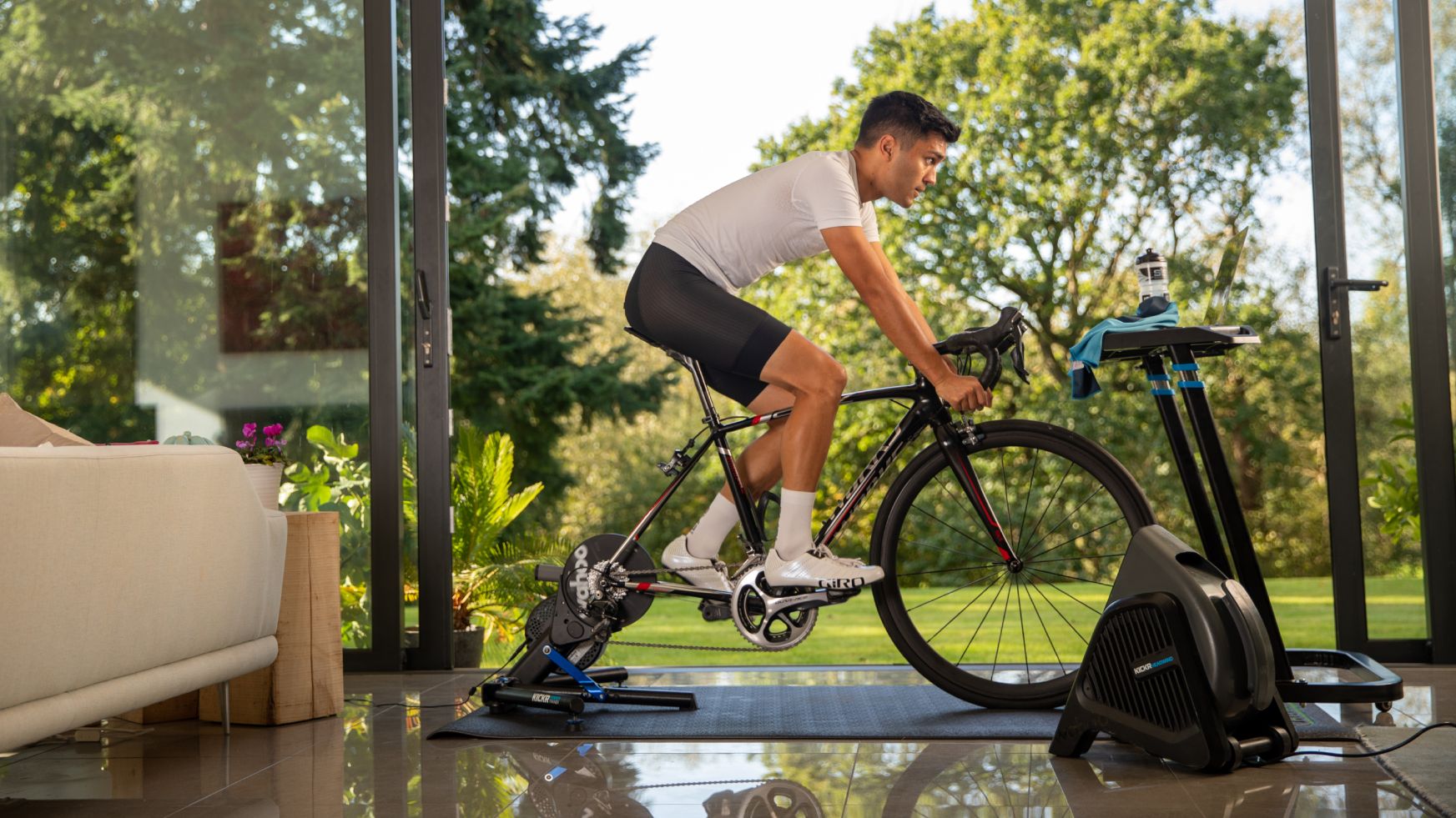 Image shows a rider cycling indoors using a Wahoo Kickr turbo and headwind.