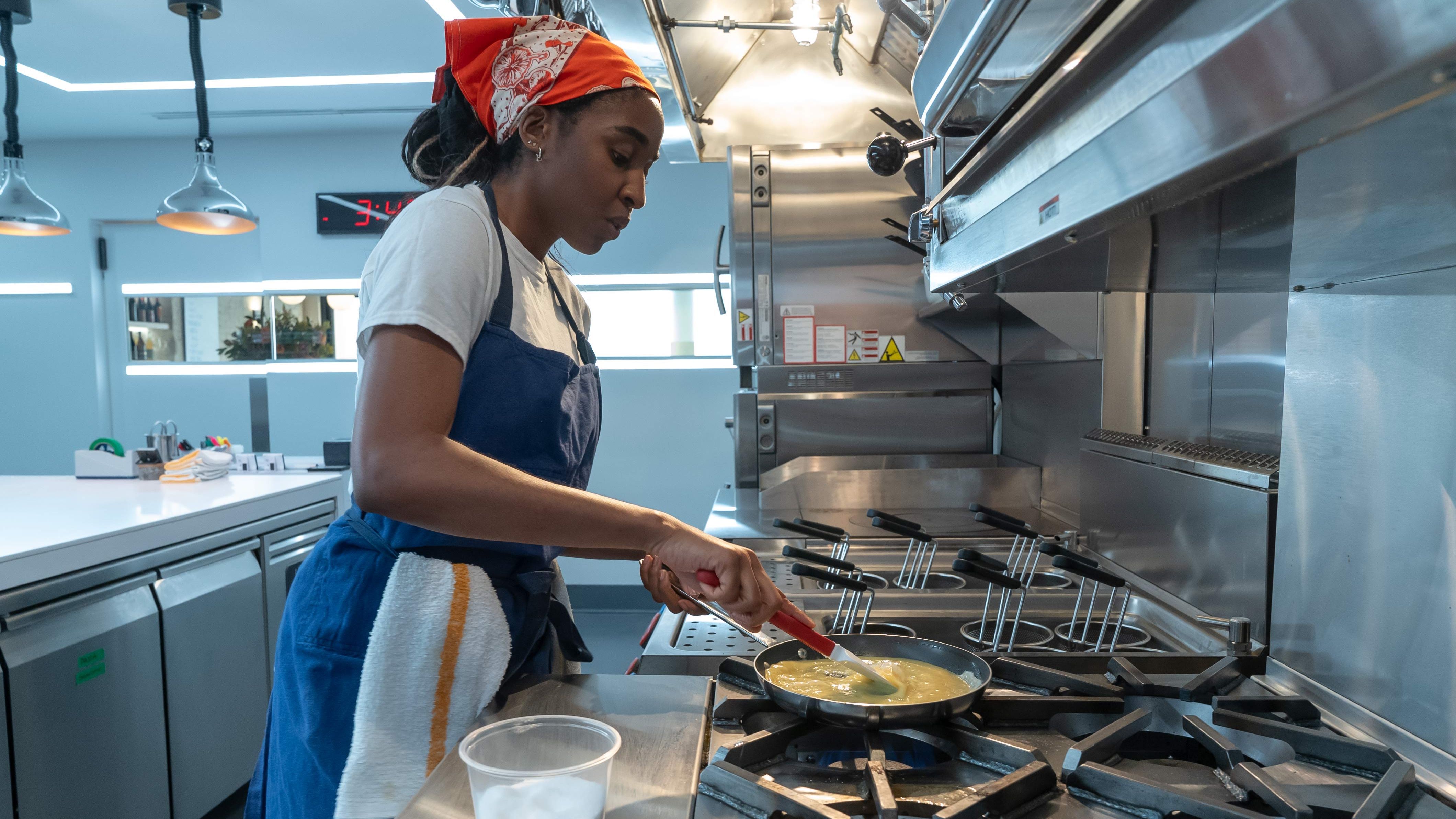 an image from The Bear season two episode 9 showing Syd making an omlette at the kitchen stove