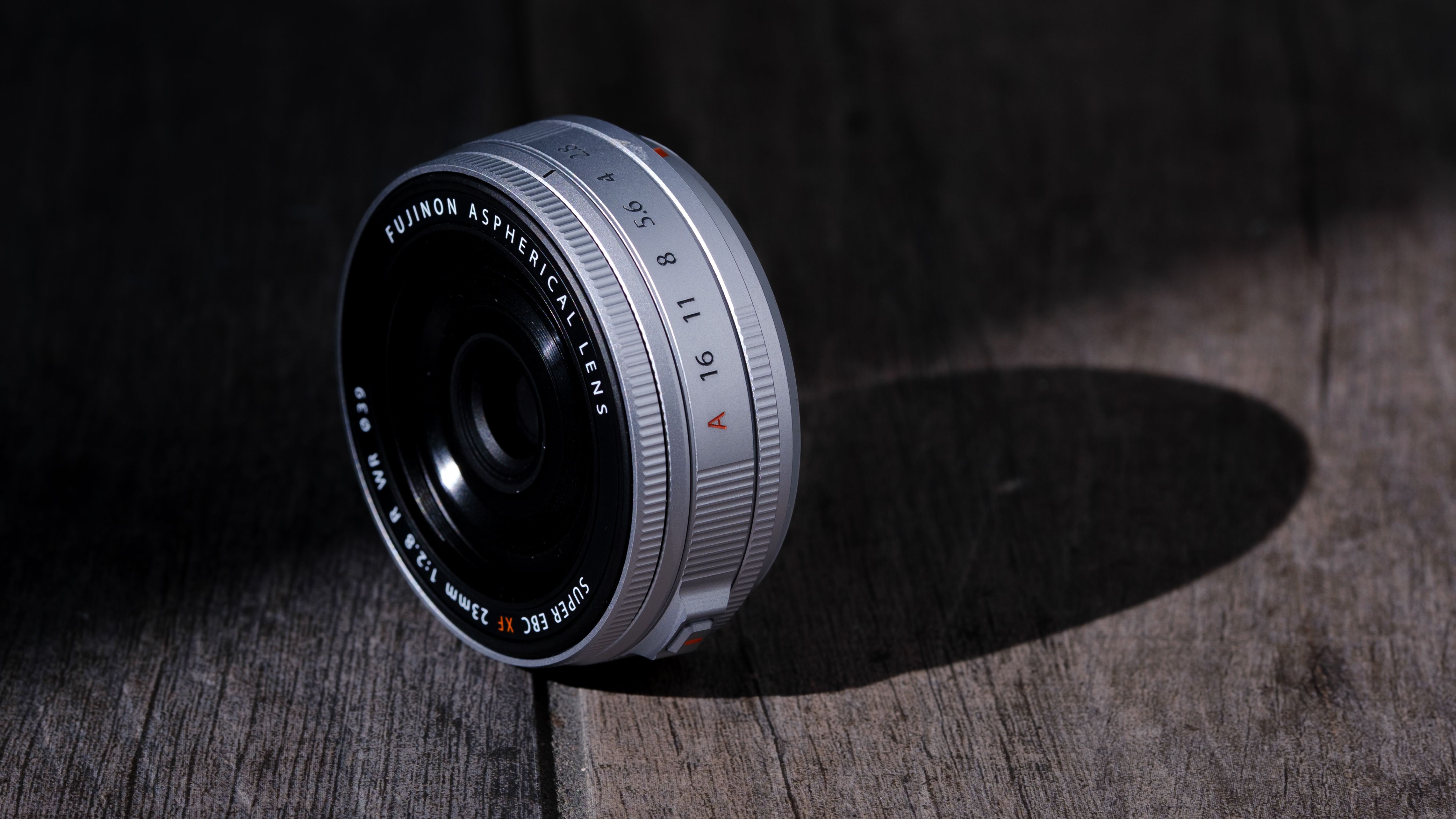 The Fujifilm XF 23mm f/2.8 R WR on a gray wood-like surface