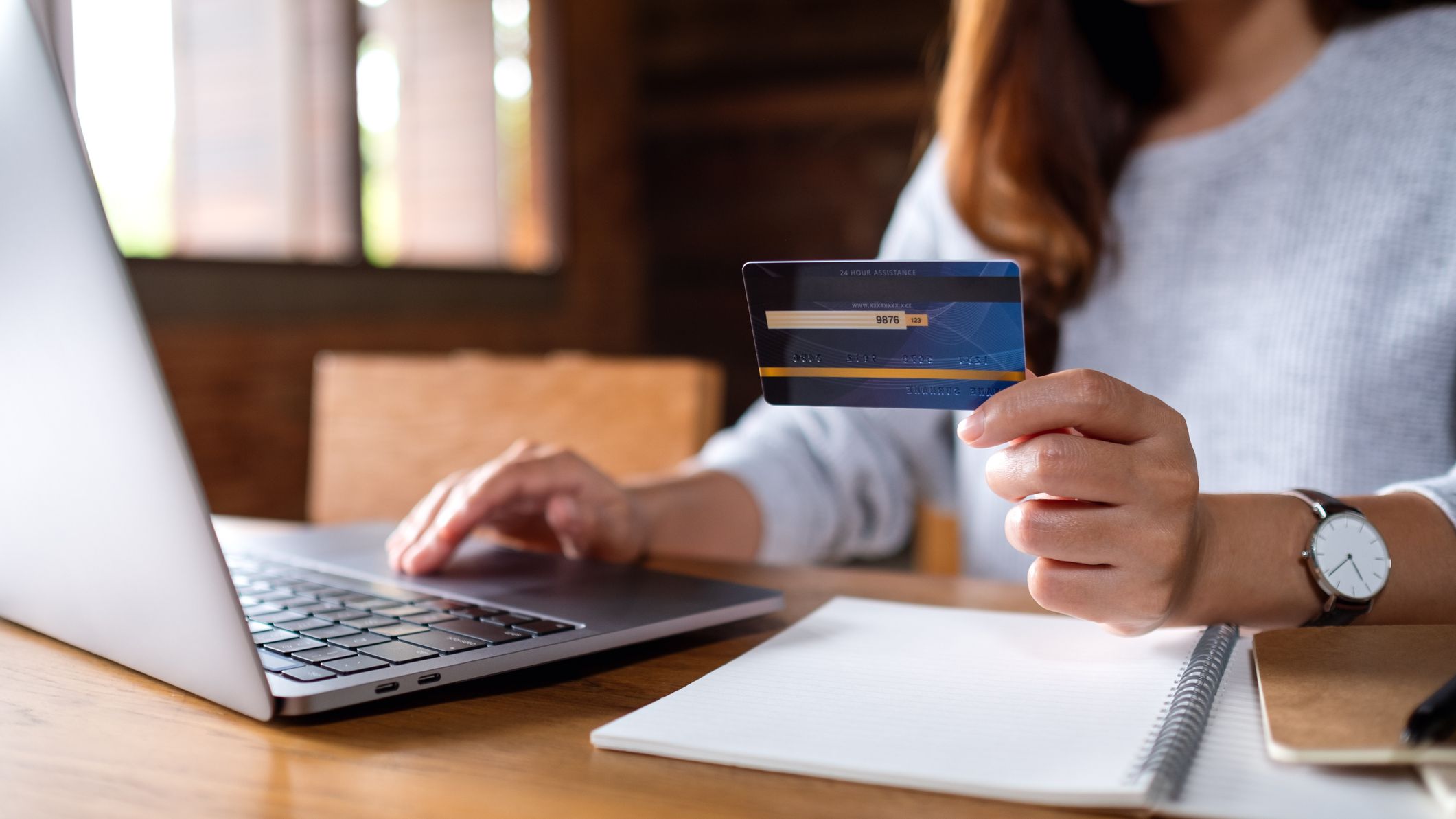 A woman holding credit card while using laptop computer for online payment