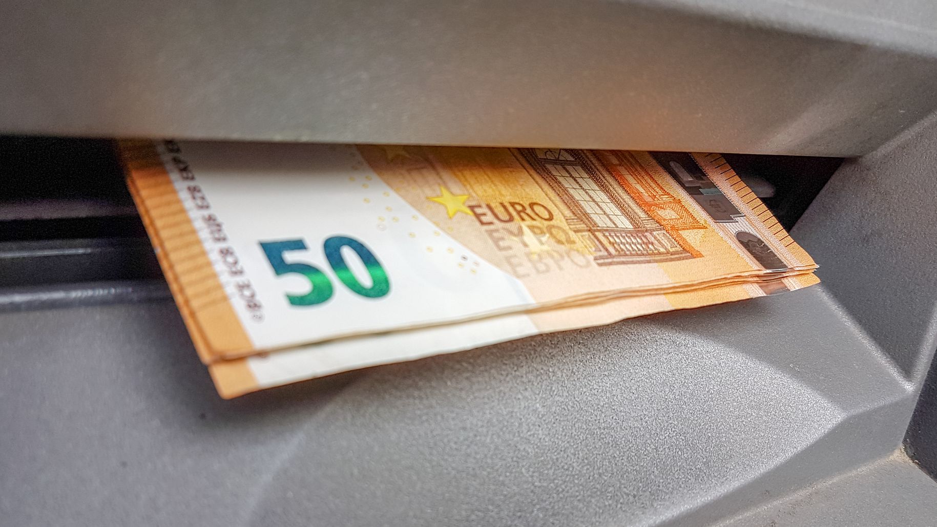 Euros sticking out of an ATM machine.