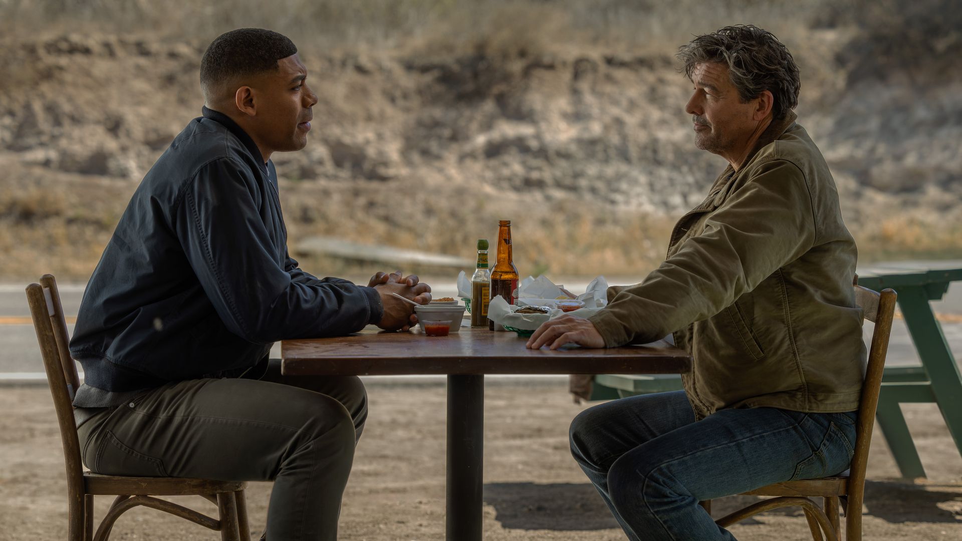 two men sit opposite each other at a table