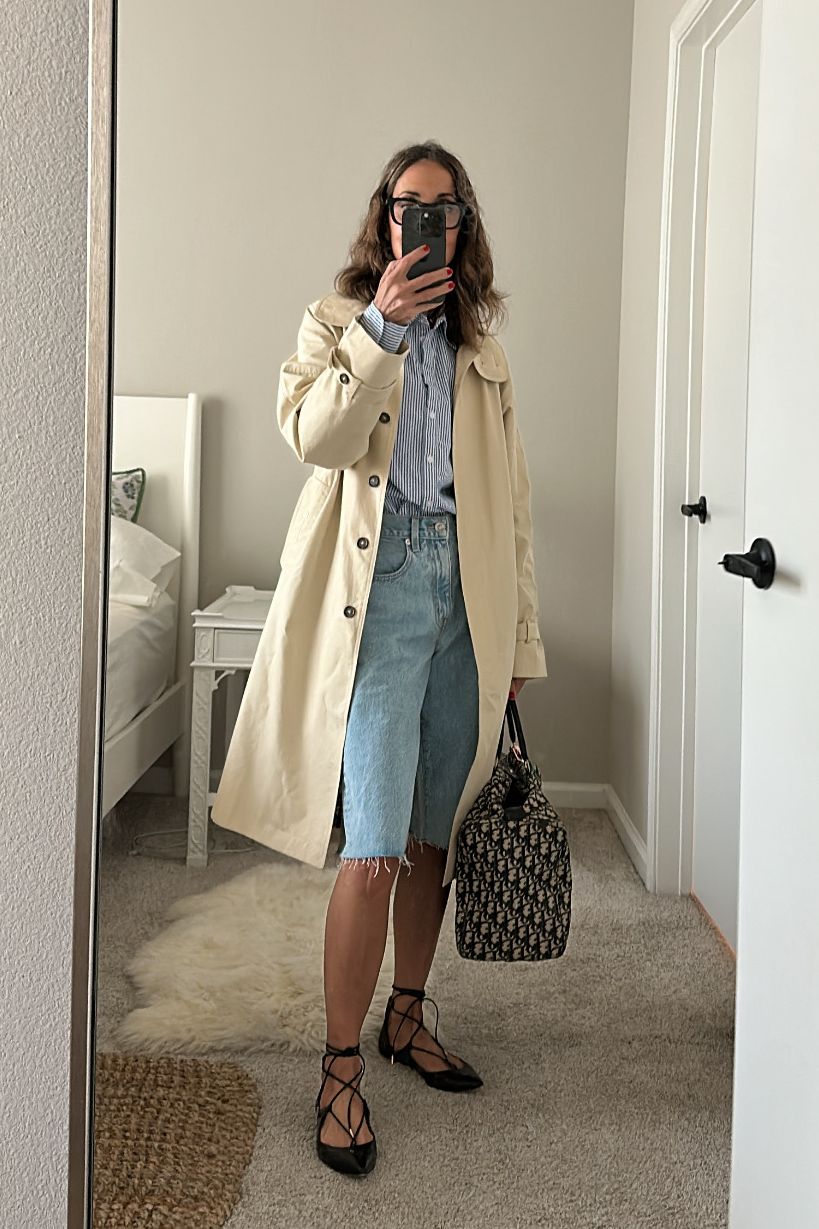 Larissa Mills wearing a trench coat, a top, denim shorts, and flats