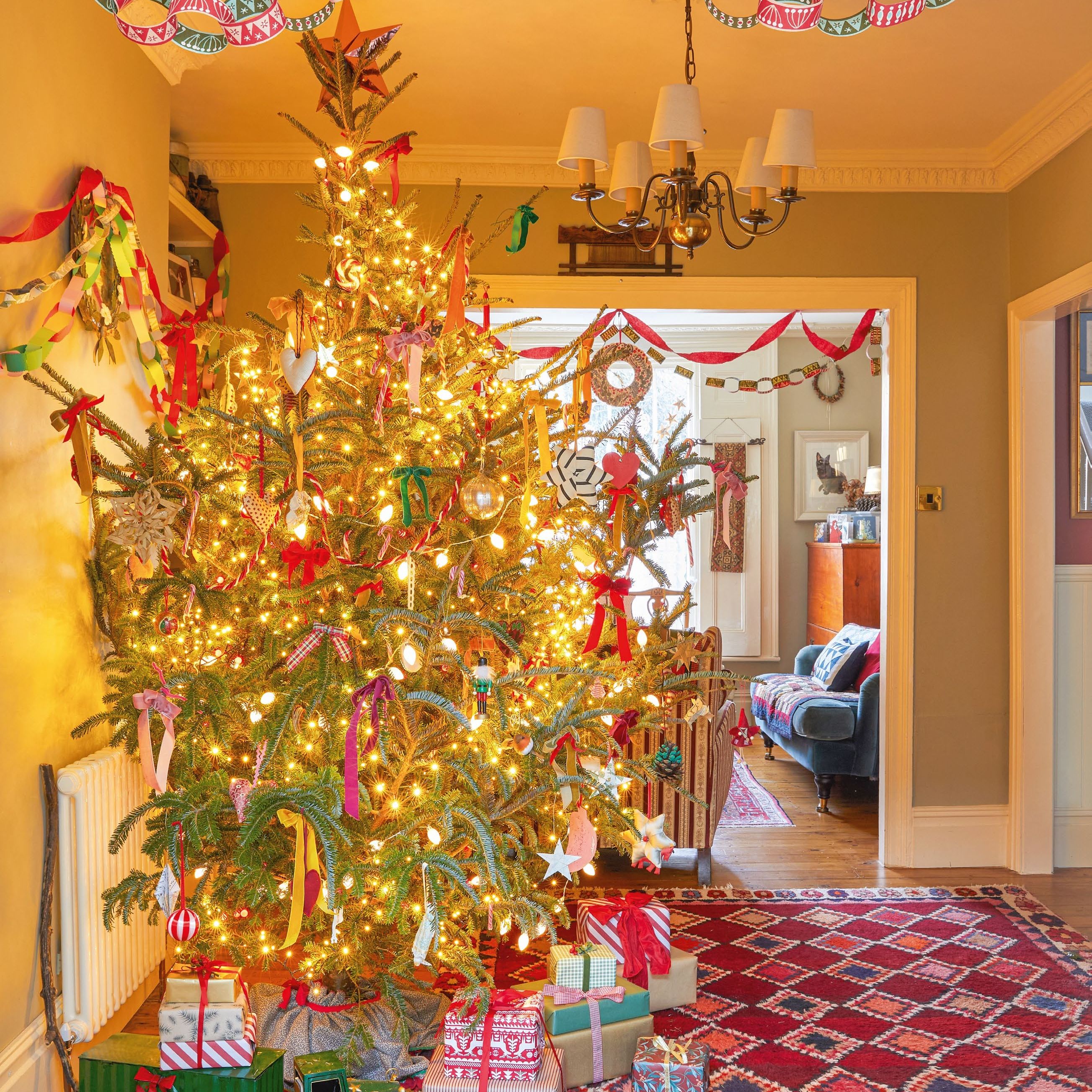 Christmas tree in a hallway decorated with colourful ribbons and lights with paper chains hung from the ceiling