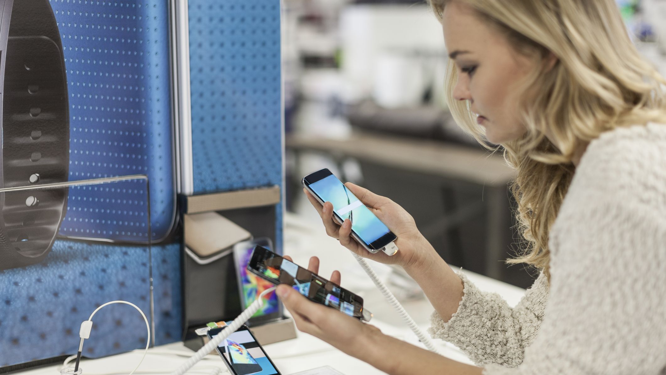 A woman comparing smart phones in a phone store