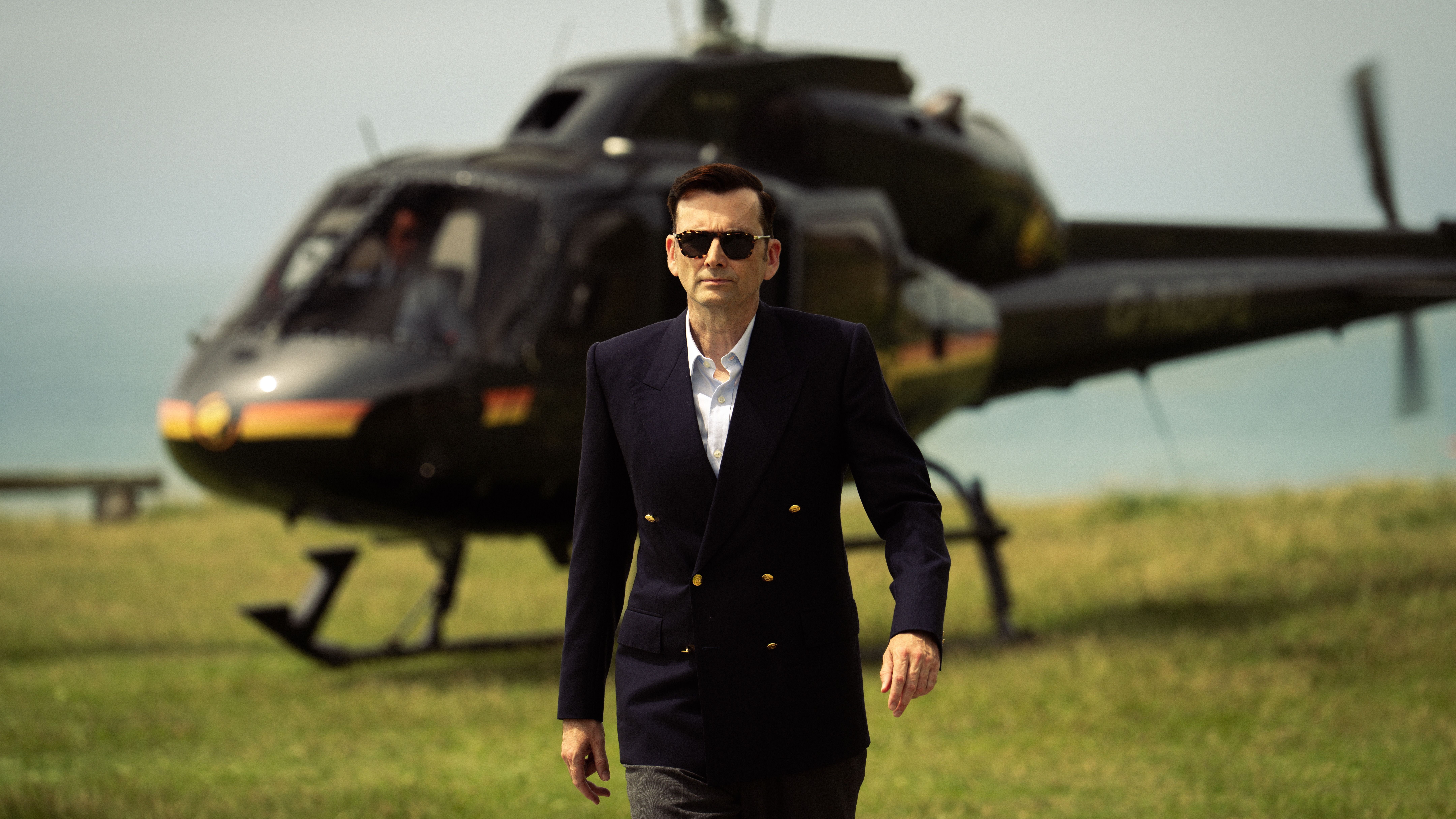 an image of David Tennant in Rivals as Tony Baddingham walking across a cliff after getting out of a helicopter