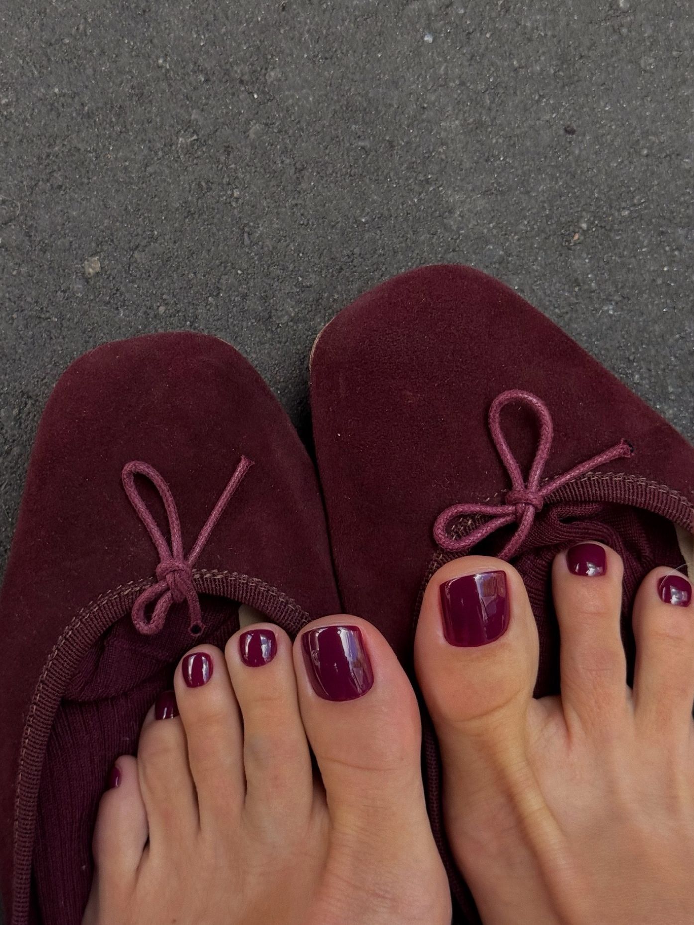 burgundy ballet flats on concrete with matching burgundy nails