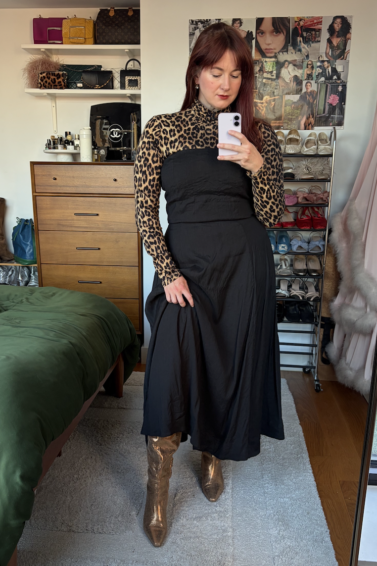 Tyler McCall wearing a leopard print turtleneck, black strapless dress, and bronze metallic boots