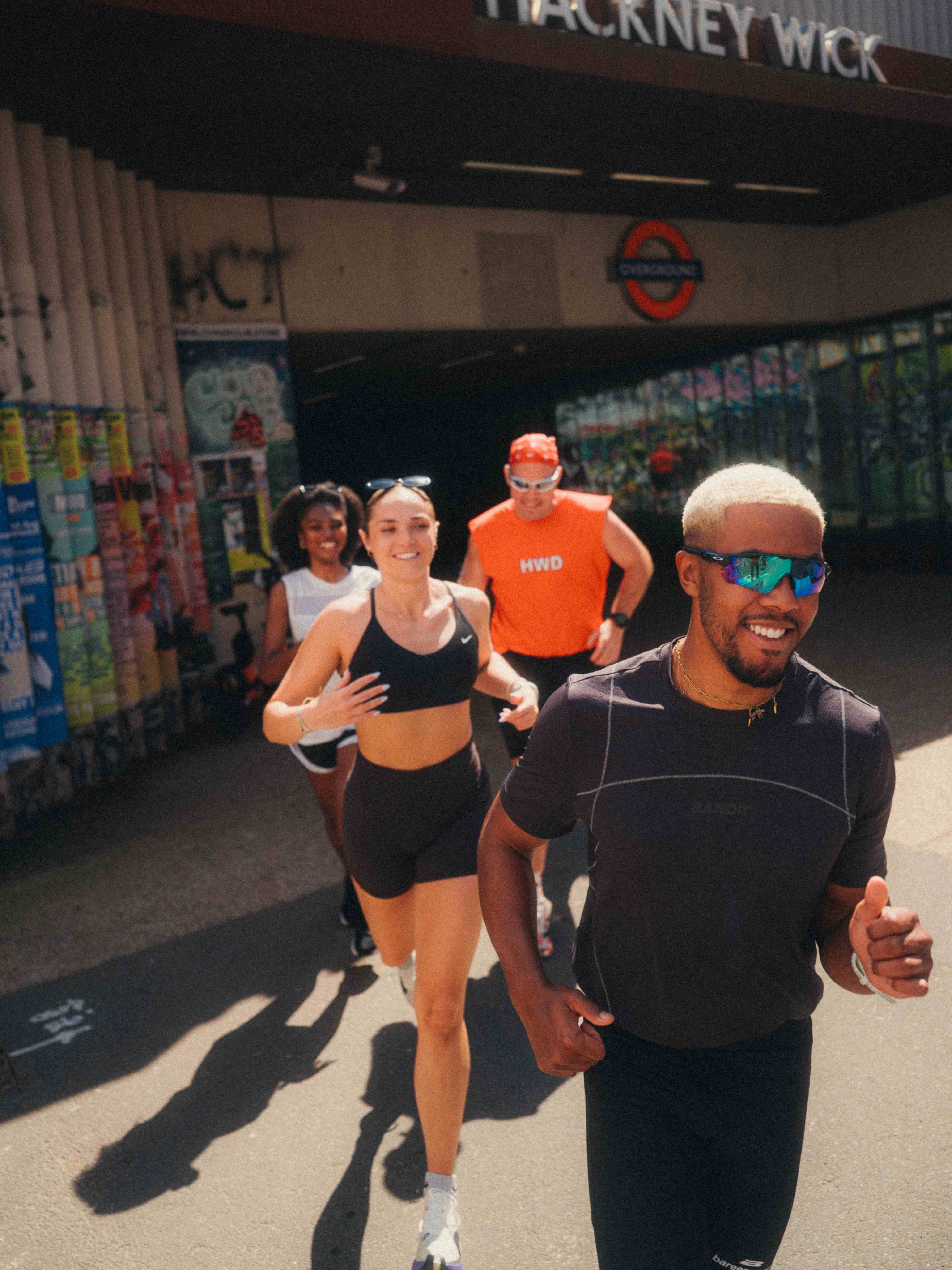 an image of four friends running across London, coming out of Hackney Wick tube station