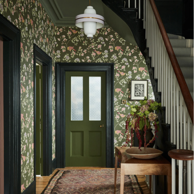 Hallway painted in dark green with green and pink patterned wallpaper
