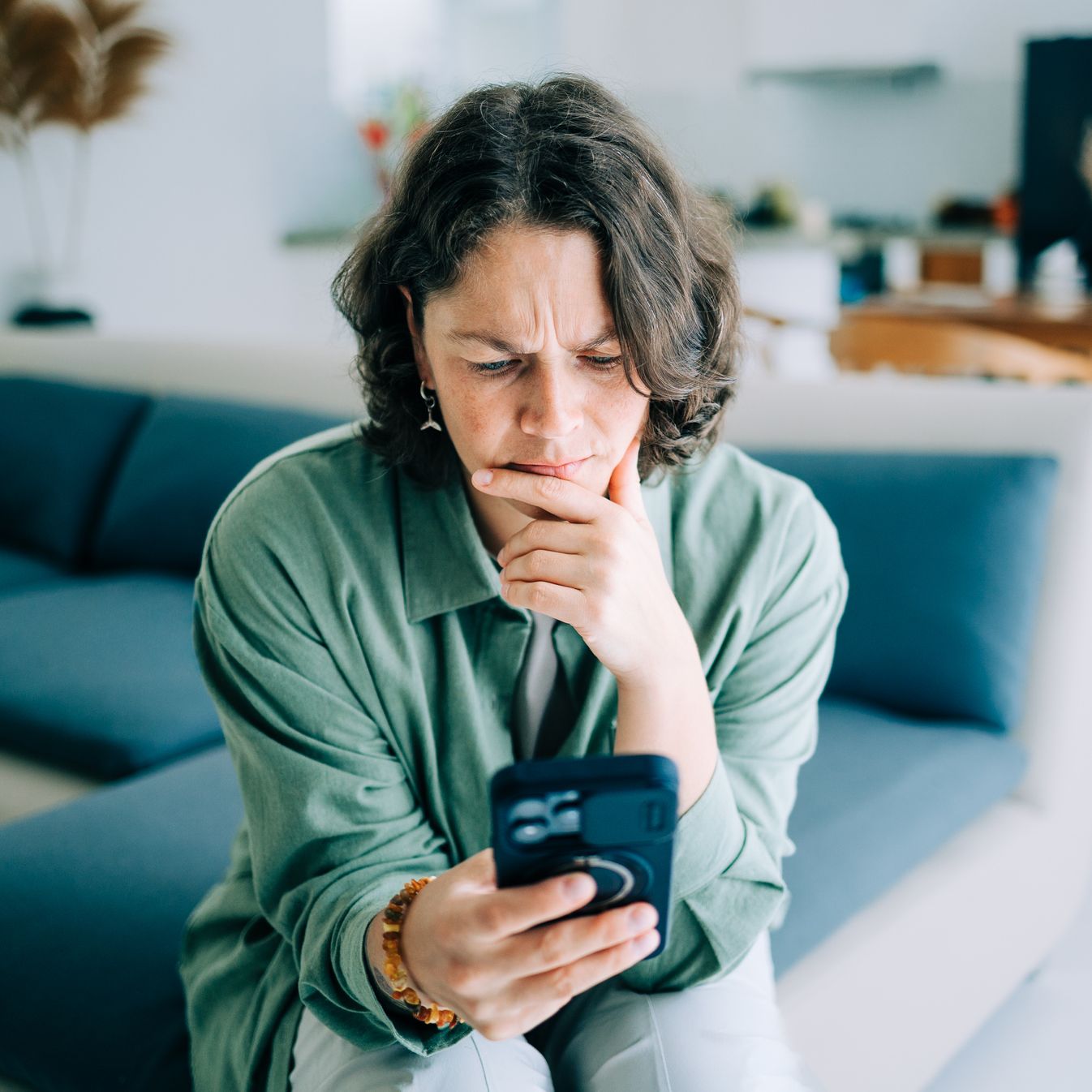 a woman furrows her eyebrows while reading on her phone