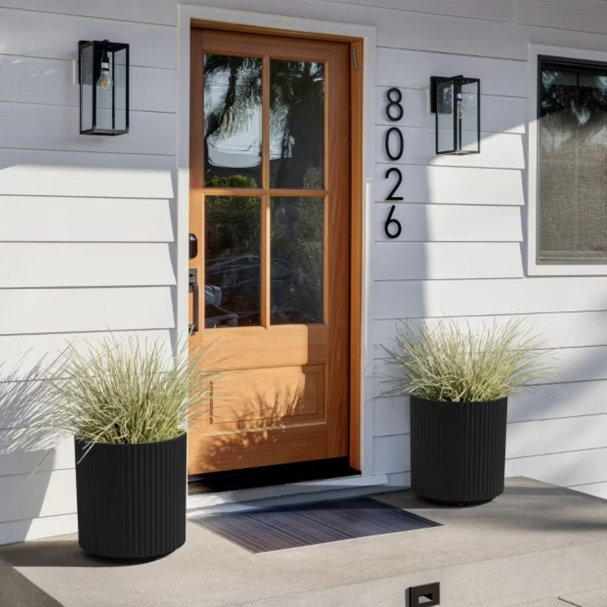 Two big black planters on a doorstep