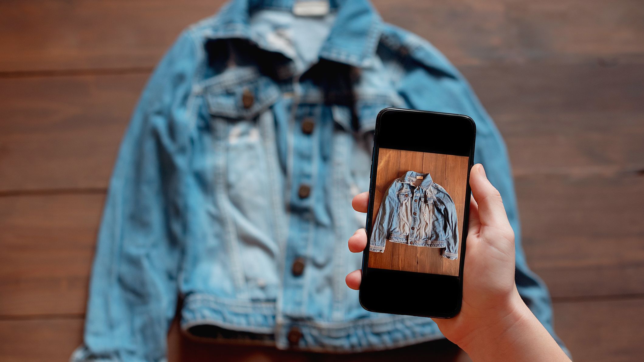 Woman taking photo of denim shirt on smartphone