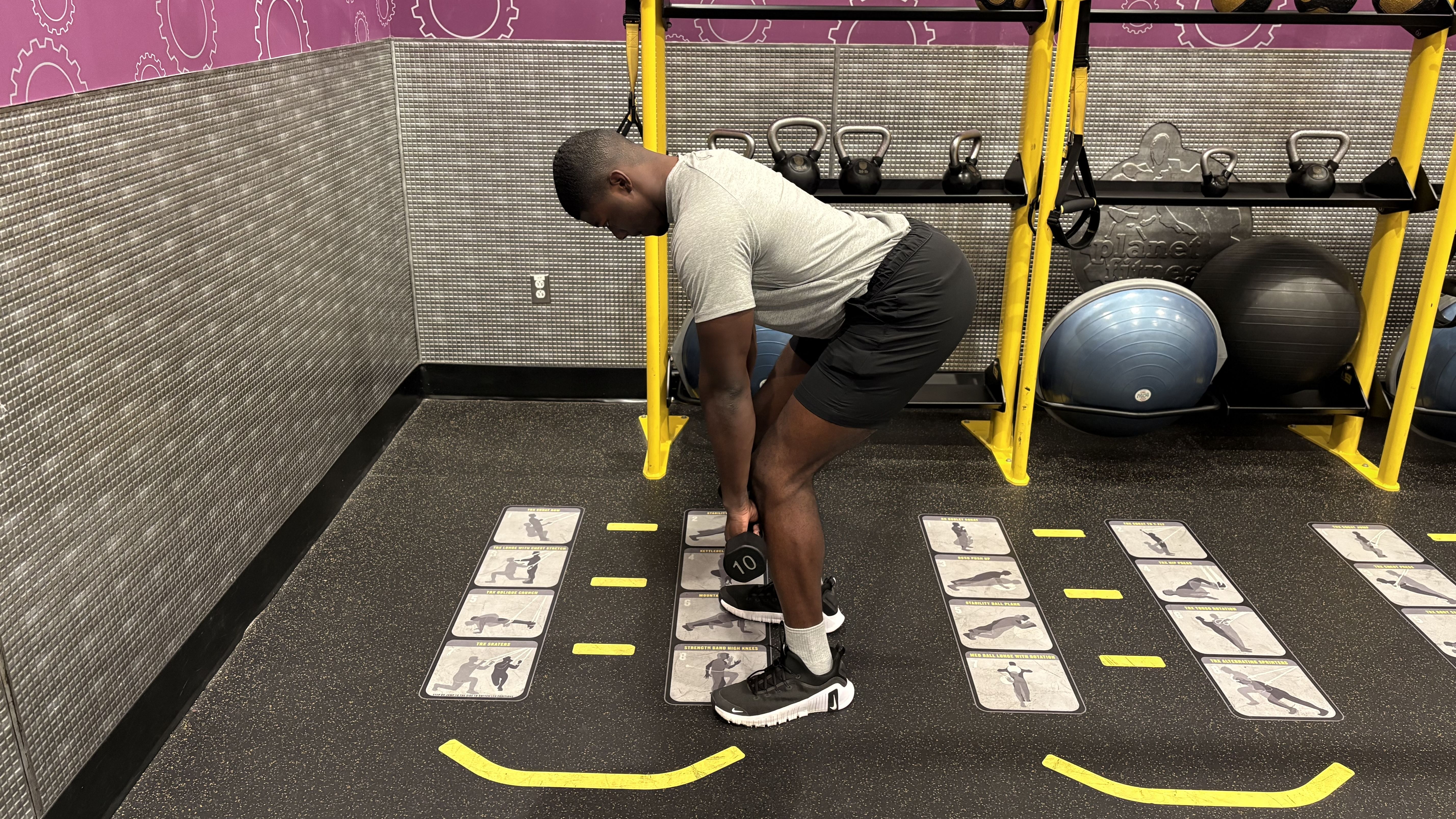 Man demonstrates a dumbbell exercise in a gym