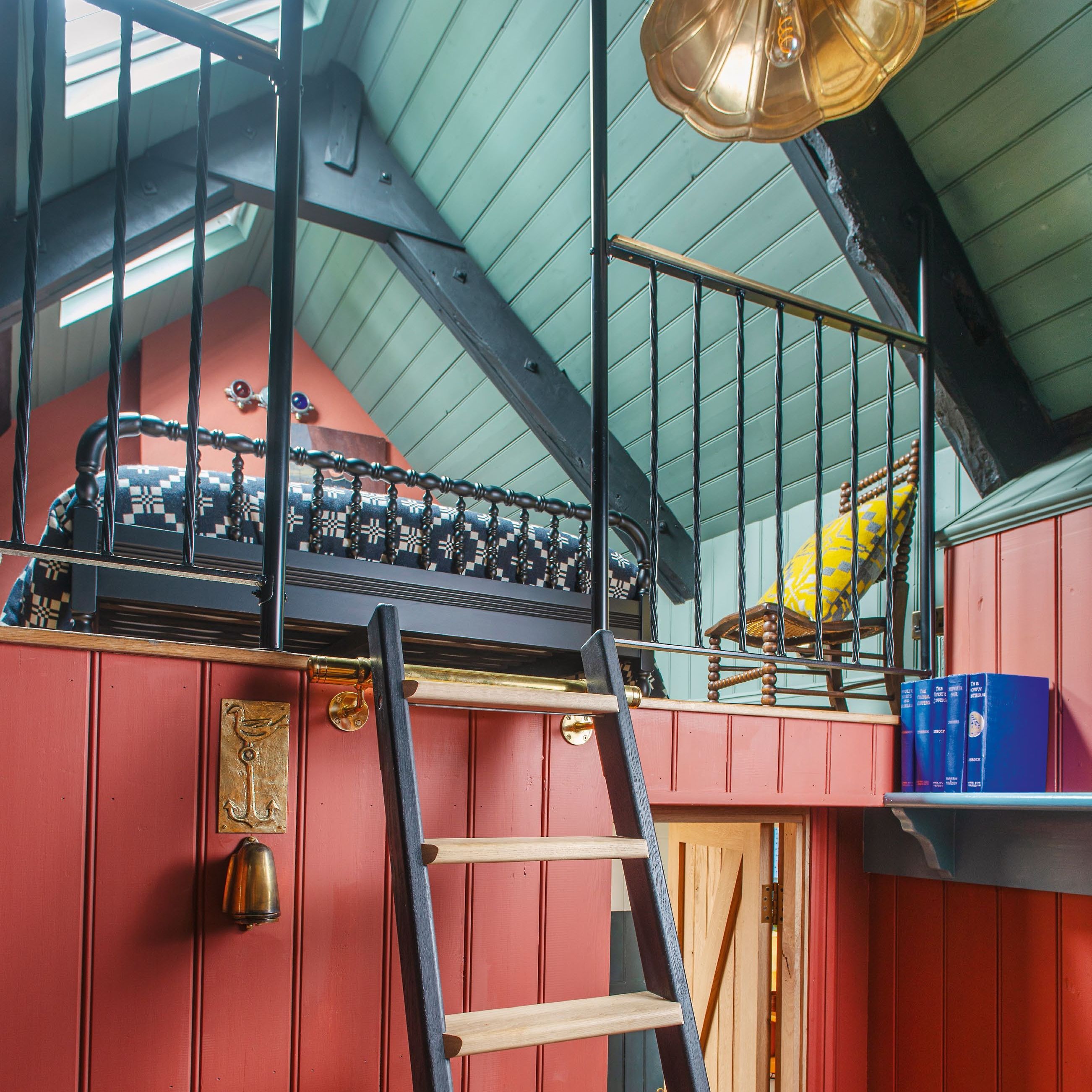 view up ladder to a mezzanine bedroom with blue green painted ceiling panelling and red wall panelling