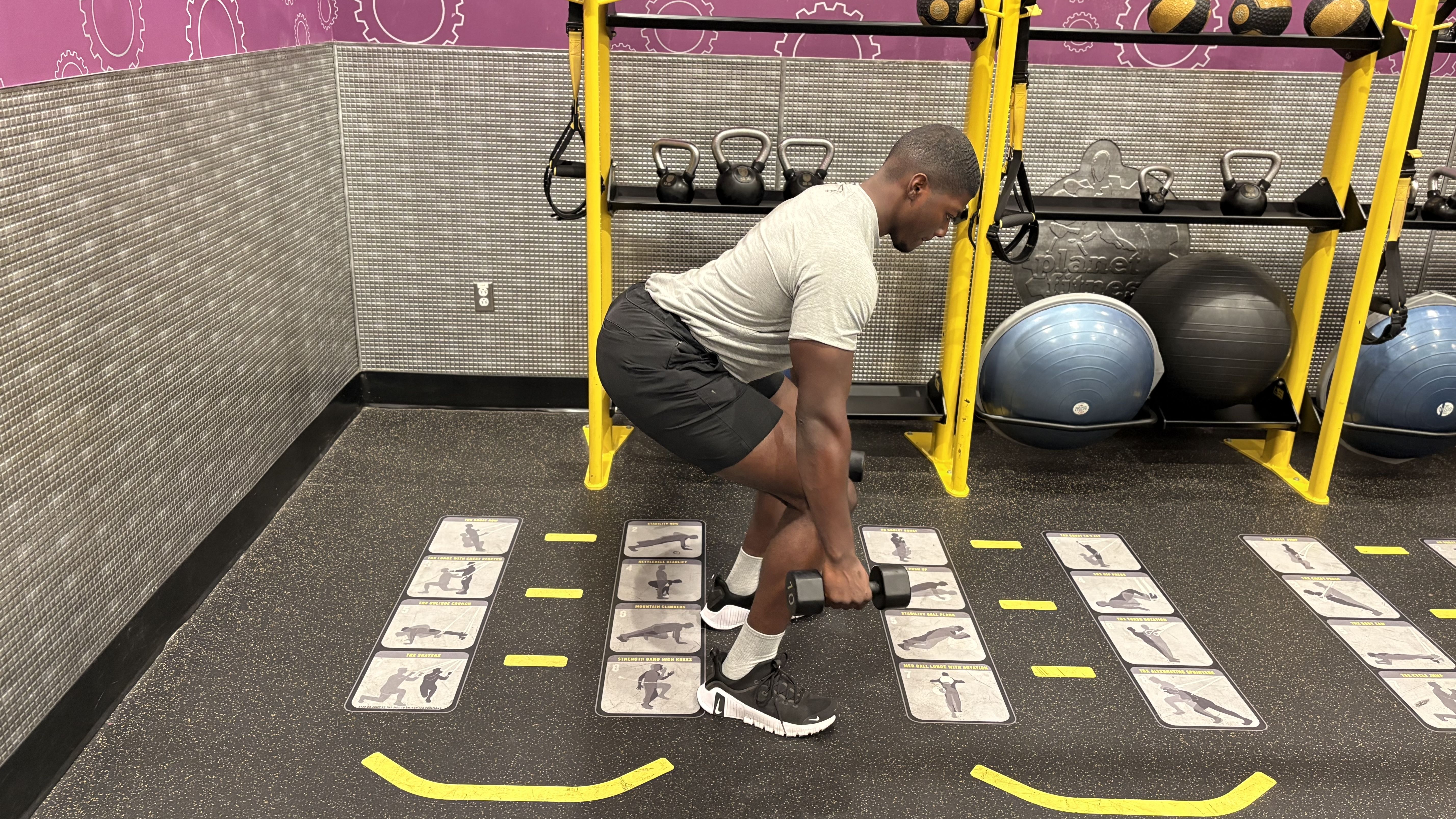 Man demonstrates a dumbbell exercise in a gym
