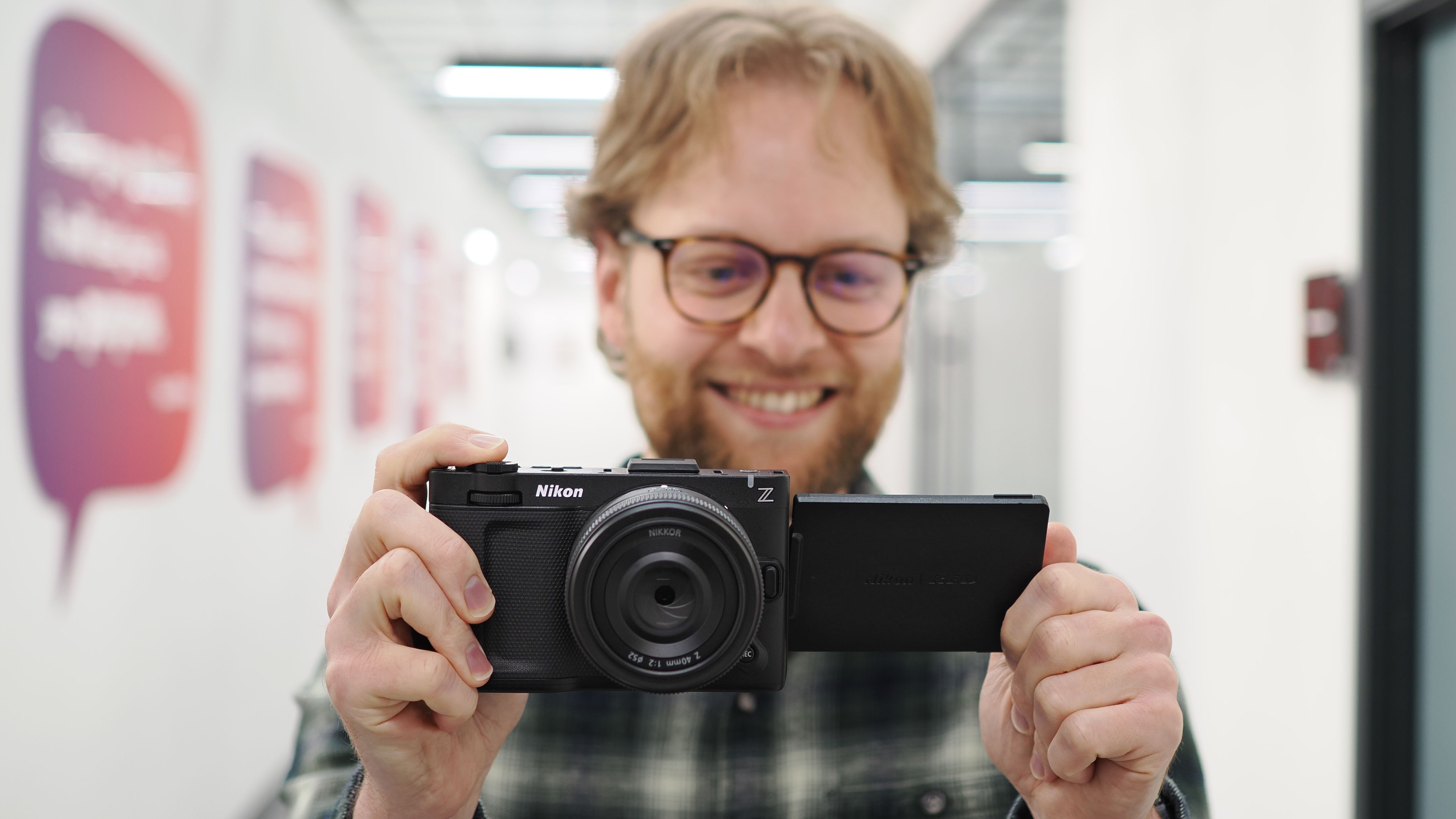 Mike Harris holding a Nikon ZR with 40mm lens in an office building