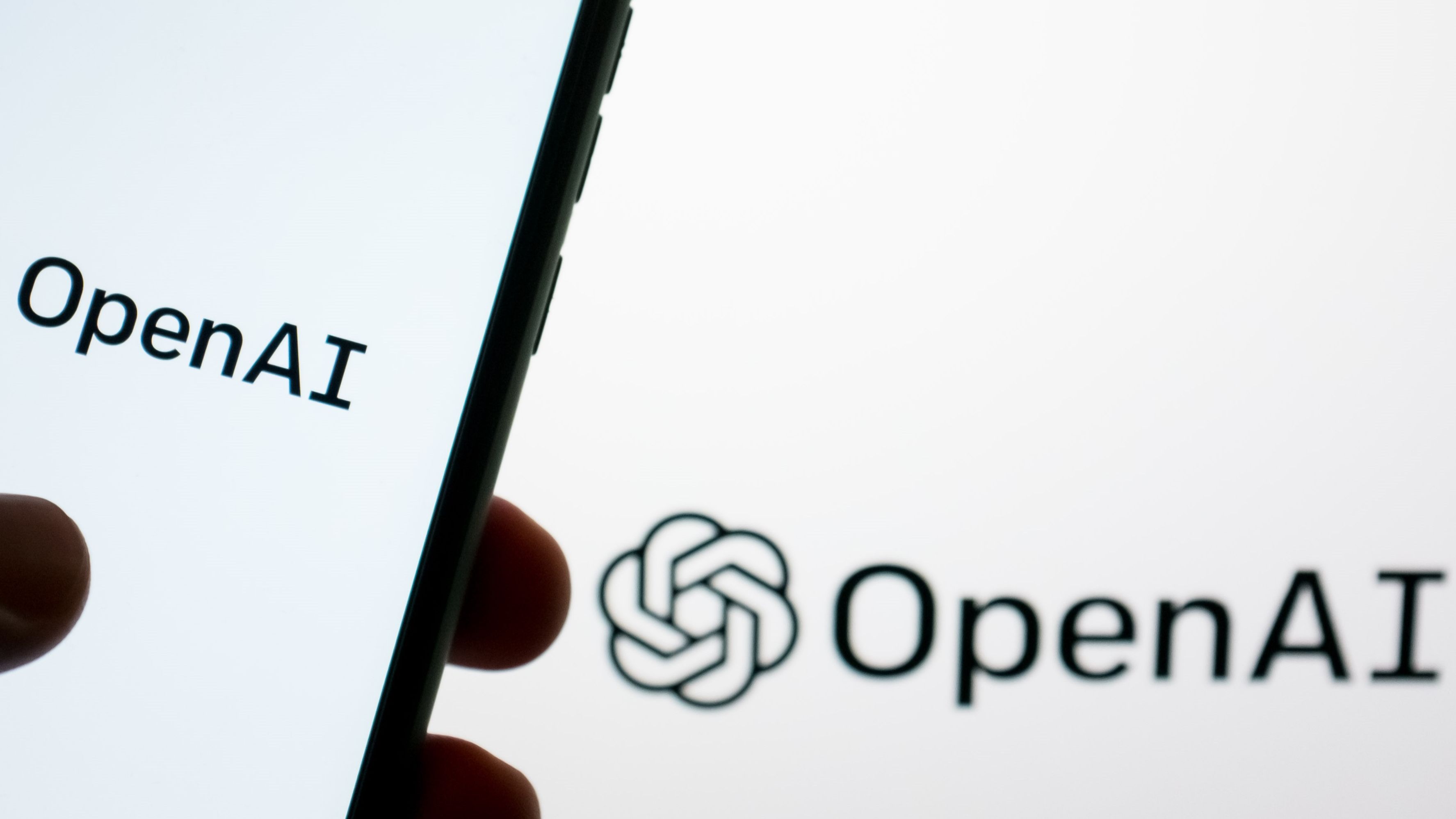 The OpenAI logo is shown on a smartphone screen and on a computer screen in Athens, Greece, on May 21, 2024