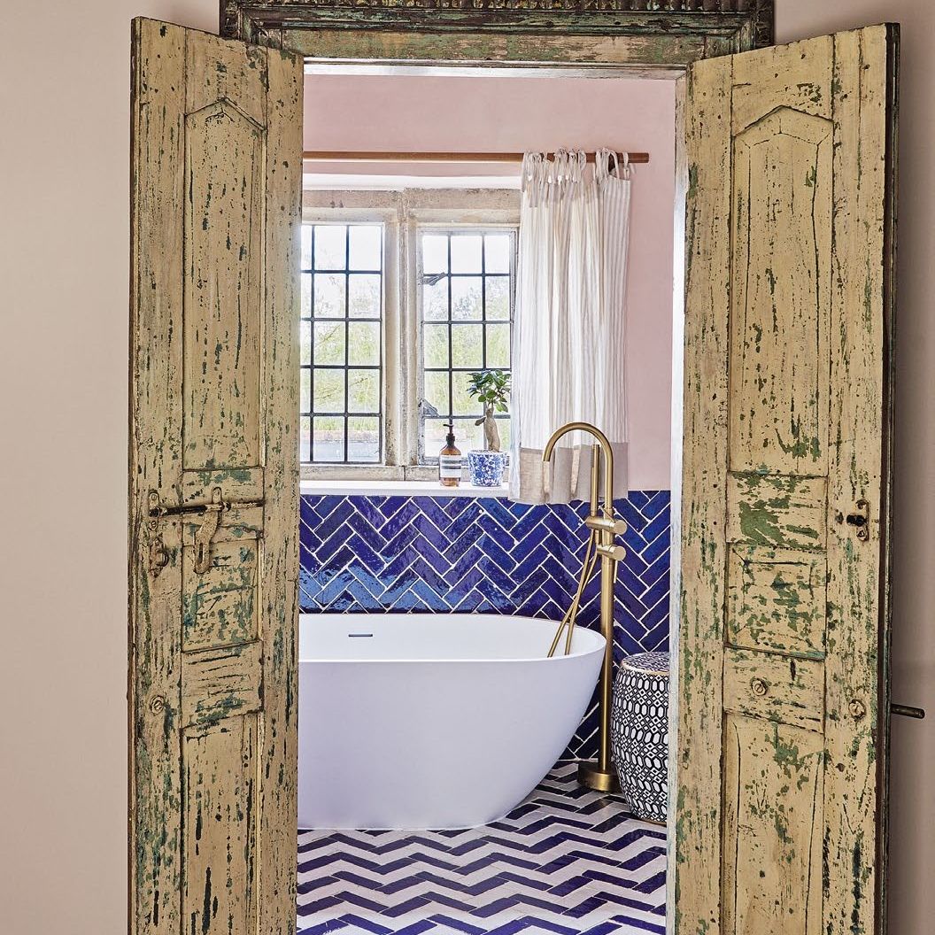Bathroom with blue and white herringbone tiles and freestanding modern bath tub